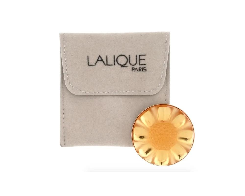 A round yellow frosted glass brooch by Lalique. The piece represents a sunflower. The golden pin backing is marked AB Cie, Lalique. The item comes in original pouch. Lalique is a French homeware, jewelry, and perfume manufacture established in 1885.