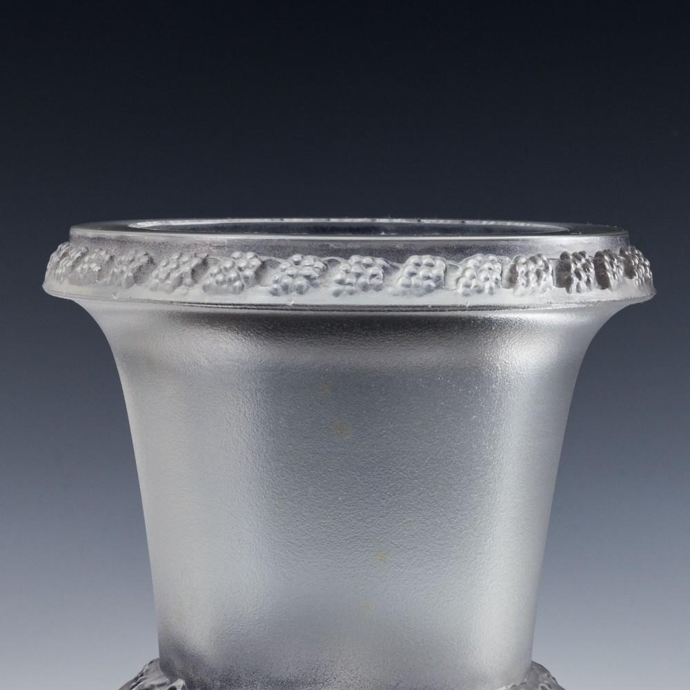 A fine example of the Lalique Quatre Tetes Des Femmes Et raisins vase. Four female masques in high relief amid grape vines, grey stain on frosted ground. Designed 1939, and manufactured early post war. Marked with acid etched upper case Lalique with