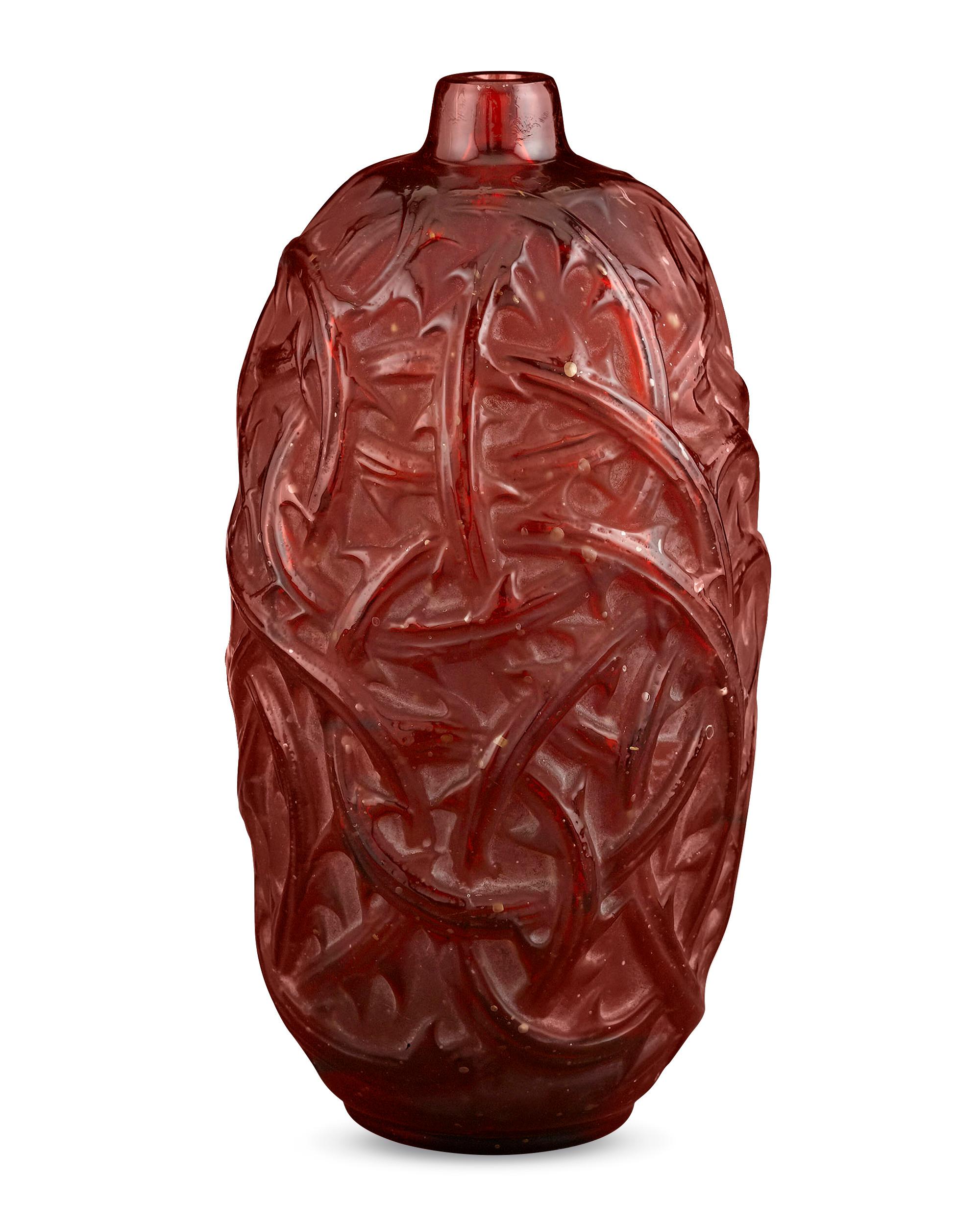 Thorned briars engulf this resplendent crimson art glass vase by the legendary René Lalique. Entitled “Ronces”, the polished vines provide a vibrant contrast to the frosted body they envelope. Originally designed for perfumer François Coty, the