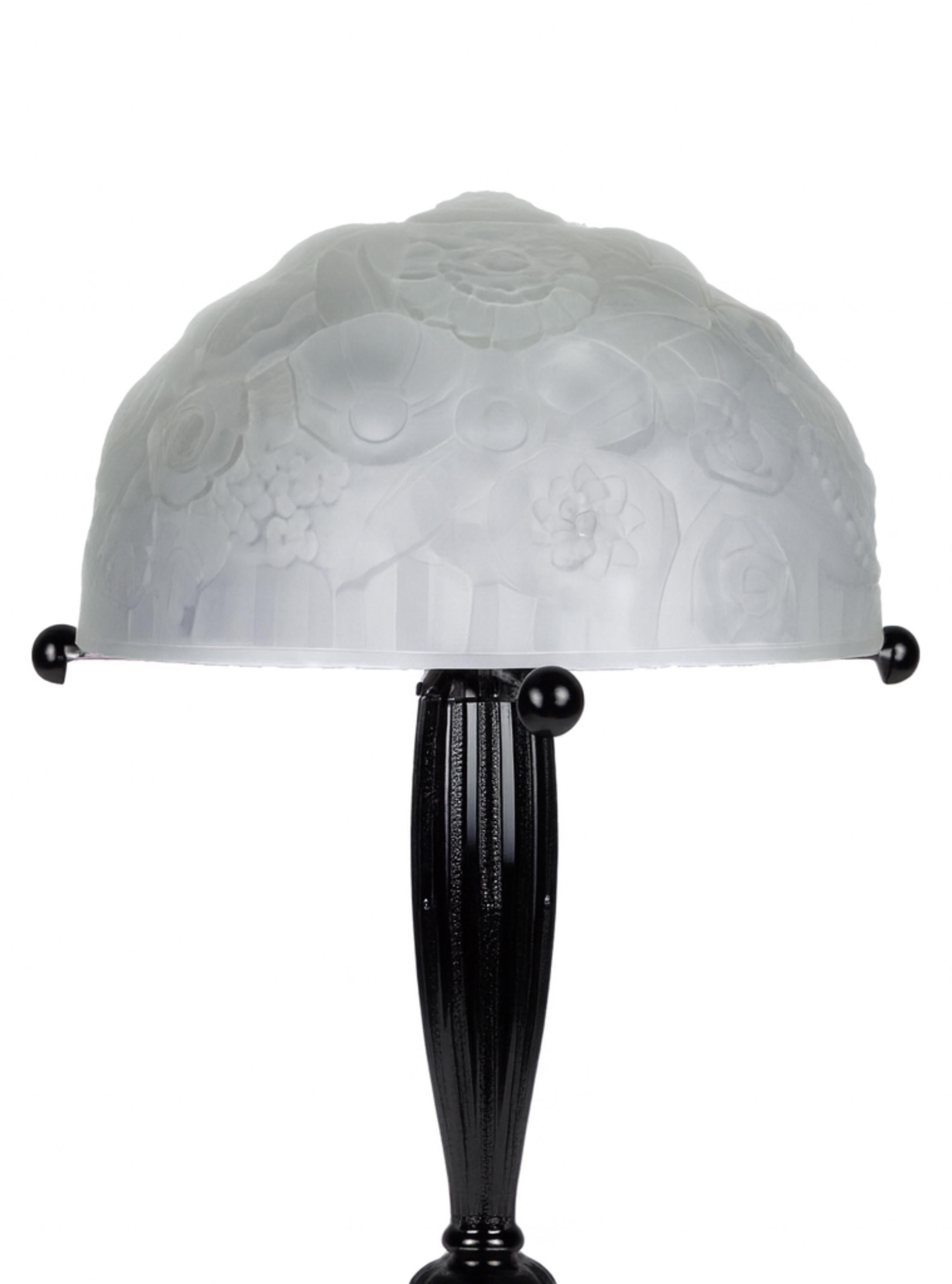 Esta lámpara de sobremesa en lacado negro repintado obra del inconfundible estilo de René Lalique, presenta un membrete y un efecto cepillado en su estructura de latón niquelado.
Las rosas de cristal grabado añaden un toque delicado, mezclando