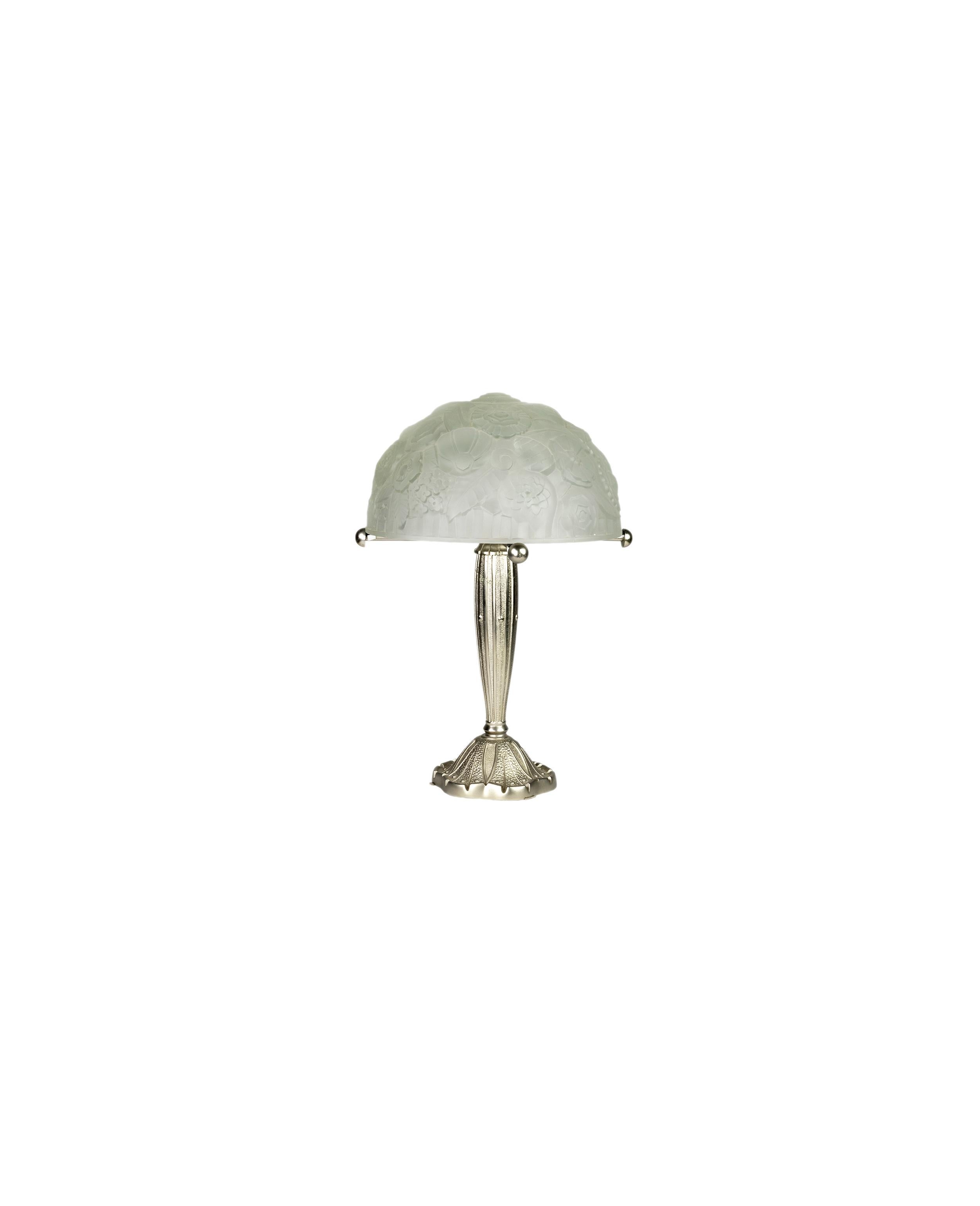 Esta lámpara de mesa encarna el estilo distintivo de René Lalique, con un membrete y un efecto cepillado en su estructura de latón niquelado.

Las rosas de cristal grabado añaden un toque delicado, mezclando sutilmente las influencias del Art