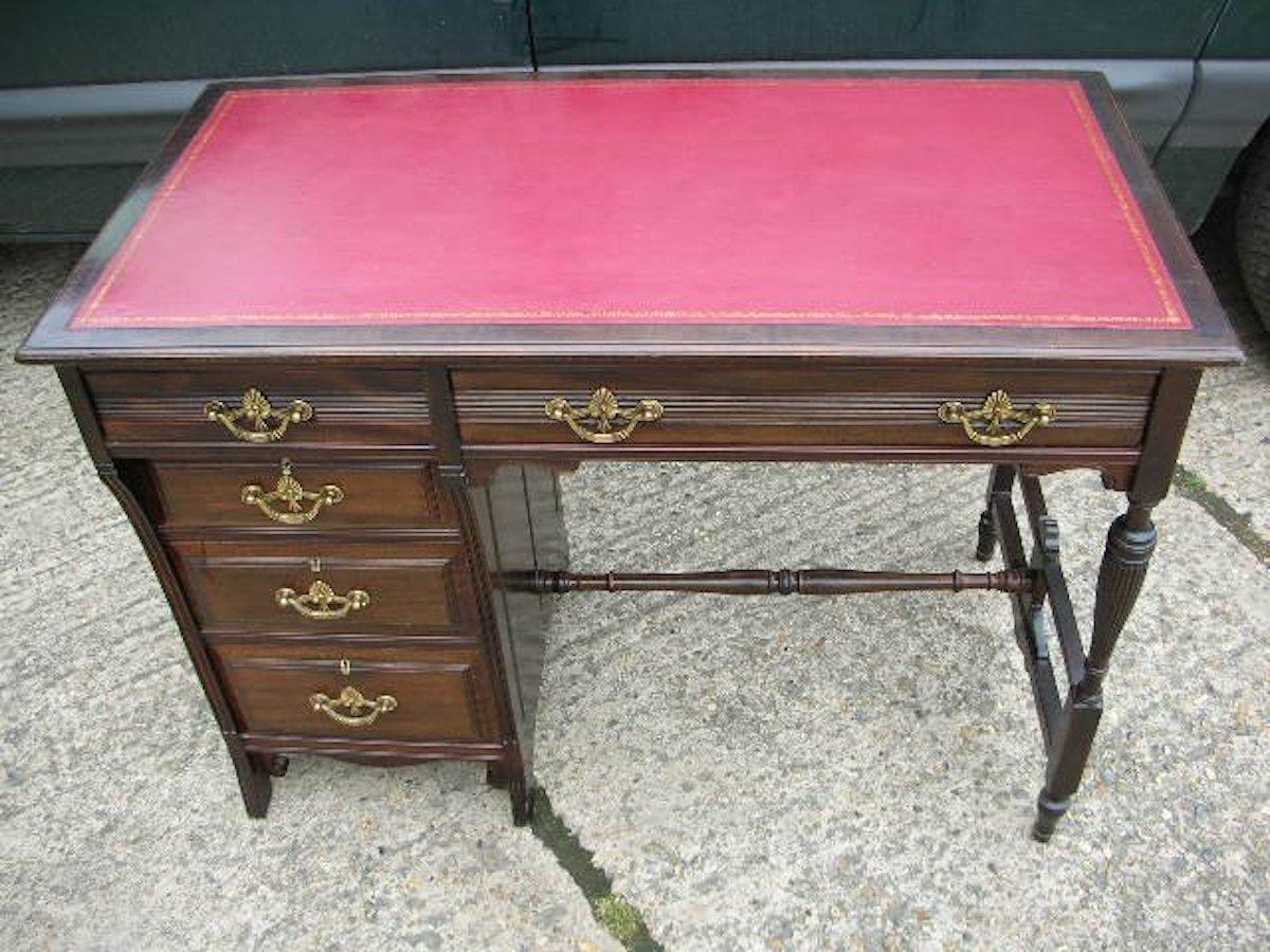 Lamb of Manchester. An Aesthetic Movement walnut and leather writing desk with a bank of four graduating drawers to the left and a large upper drawer to the right with turned and fluted legs united by upper and lower turned side