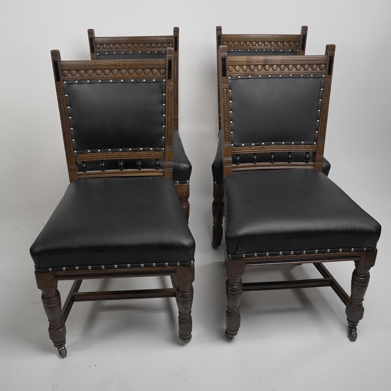 Lambs of Manchester A Set of Four Aesthetic Movement Oak Dining Chairs with carved and part ebonised details, professionally reupholstered in a quality matt black leather.