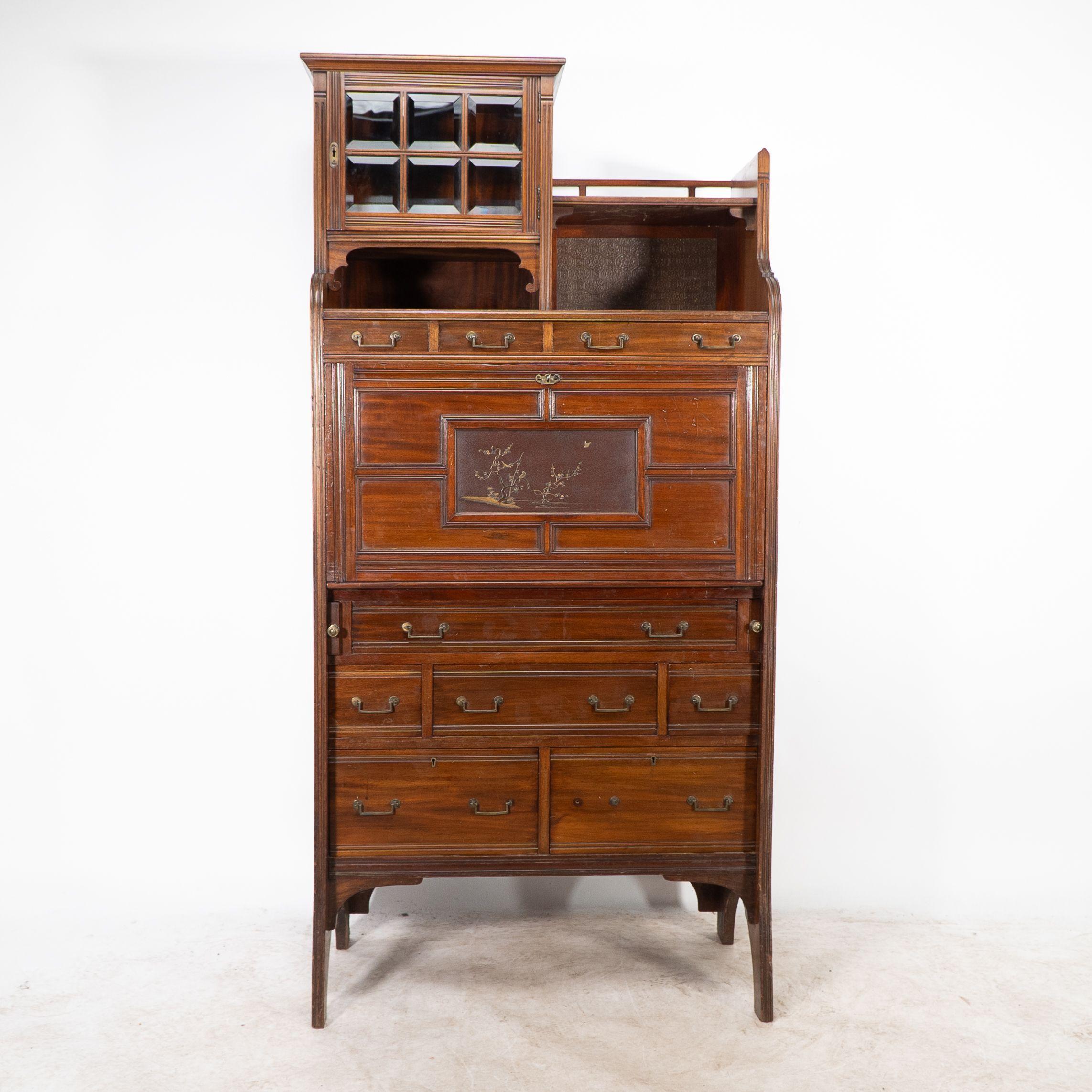 Lamb of Manchester. Libreria secretaire anglo-giapponese con pannello laccato giapponese nella zona di scrittura a ribalta, una serie di cassetti e un armadietto nella parte superiore con vetro smussato sull'anta, girasoli intagliati sui lati.
Il