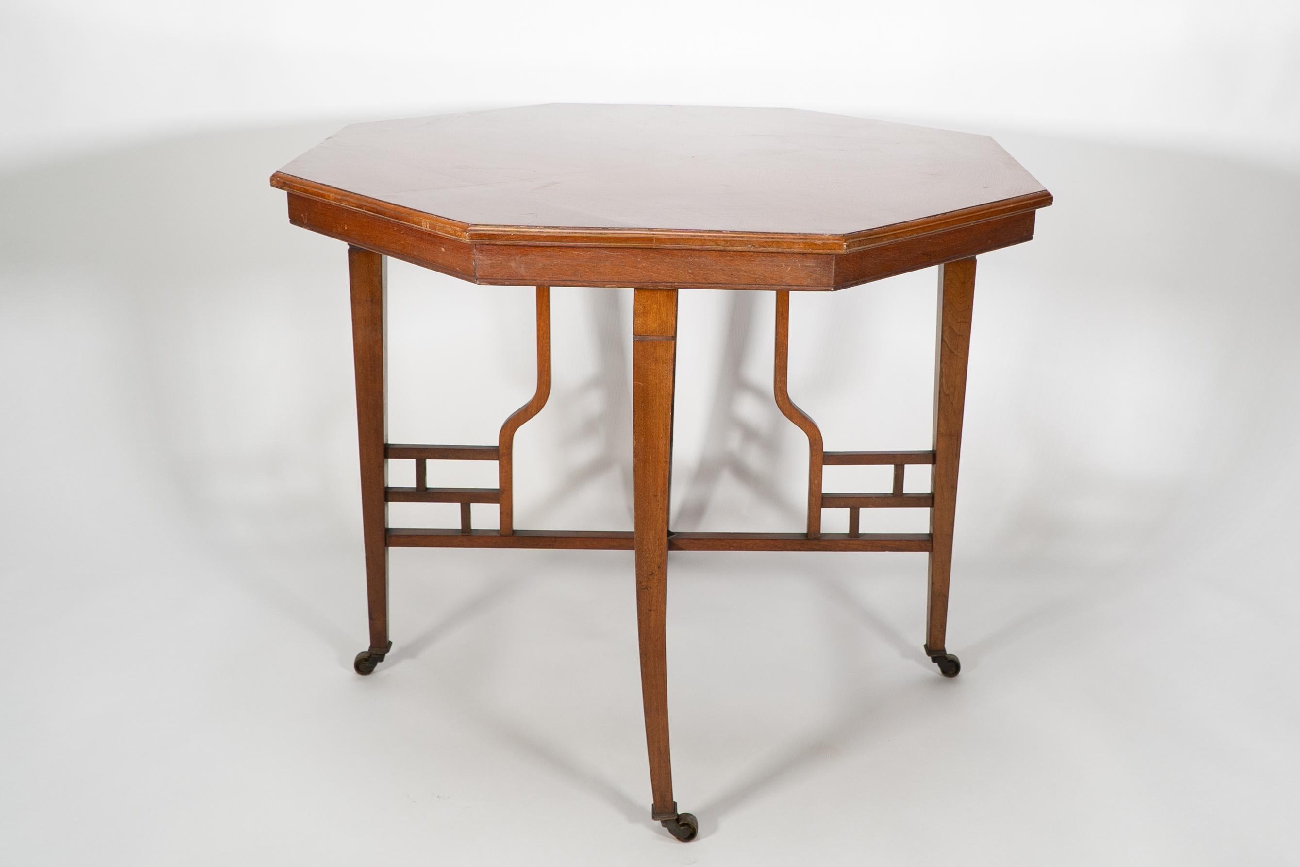 Al estilo de Edward William Godwin.
Mesa de centro octogonal de caoba flameada anglojaponesa, rara y de gran calidad, sobre cuatro patas ahusadas, unidas por una cruceta calada anglojaponesa con soportes verticales y un remate en el centro de la