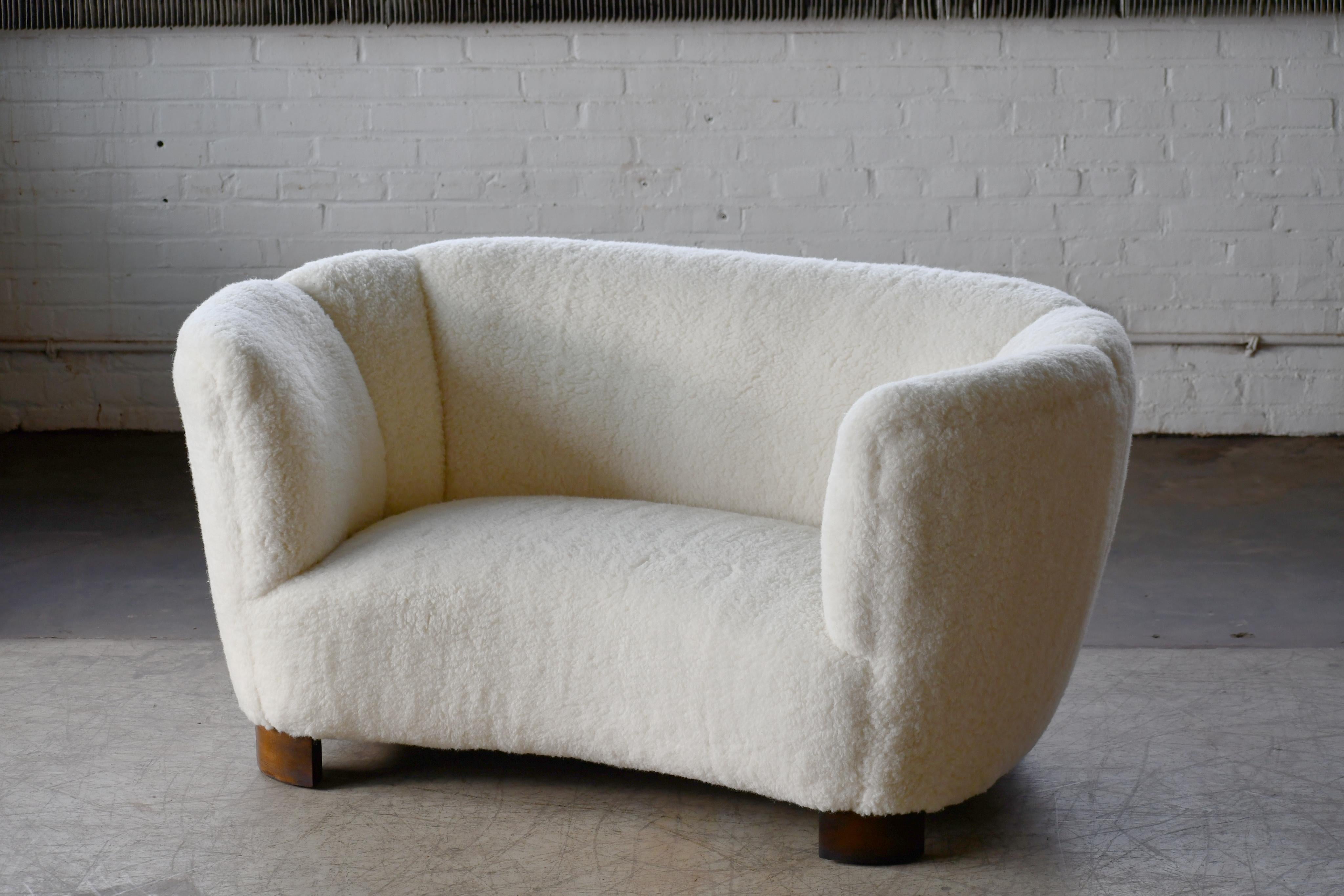 Banana shaped Viggo Boesen style curved two-seat sofa or loveseat made in Denmark in the 1940s. This sofa will make a strong statement in any room despite the smaller size. Beautiful round lines and iconic block feet normally associated with