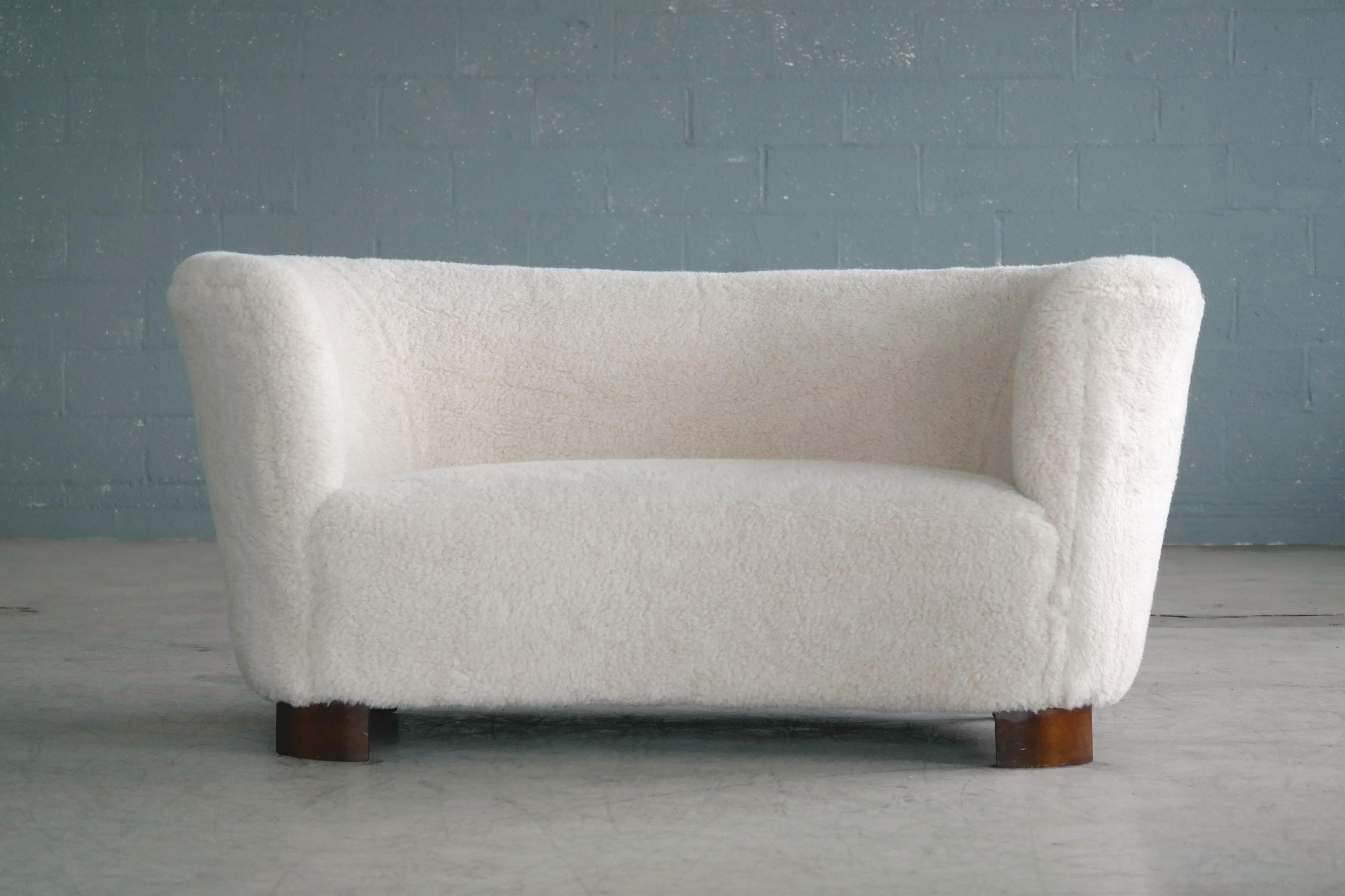 Viggo Boesen style curved two-seat sofa or loveseat attributed to Slagelse Møbelværk and Designer Viggo Boesen made in Denmark, circa 1940. This sofa will make a strong statement in any room. Beautiful round lines and iconic block feet typical of