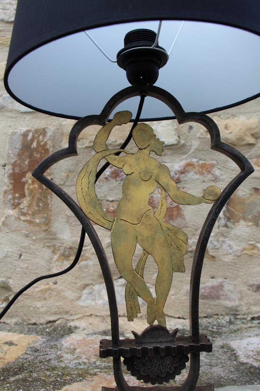Edgar BRANDT (1880 - 1960) Table lamp in hammered wrought iron with anthracite and gold patinas. A dancer, with an openwork cutout, is set in the center of a frame with two angled and moving blades with a small rectangular denticulated spacer, fixed