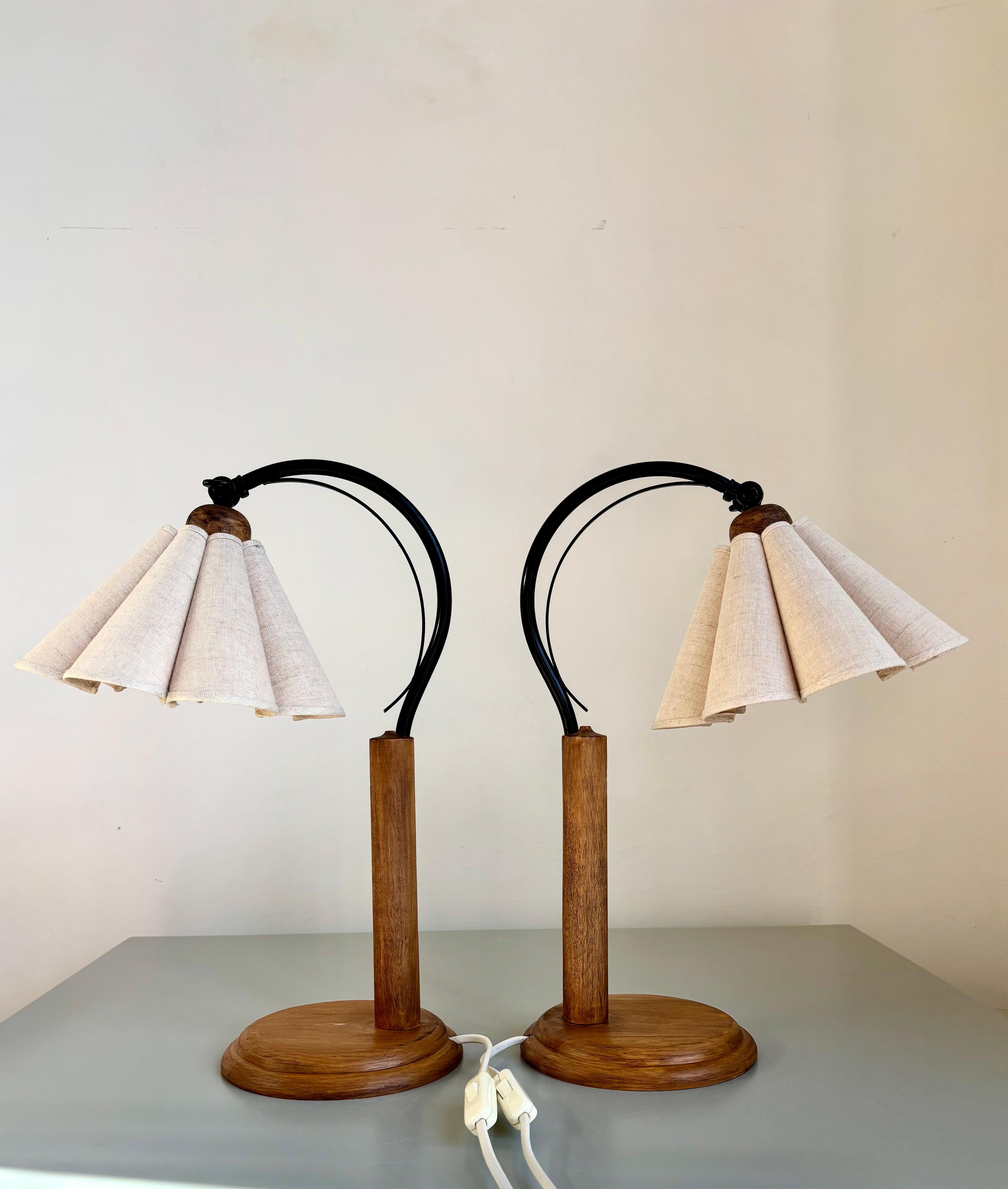 Vintage art deco style table lamps manufactured by Lamp Gustaf AB in Sweden in the 1980s.
Solid circular matte brown treated pine wood base with black lacquered metal swan neck. Original draped flower like beige sand colored linen shades adjustable