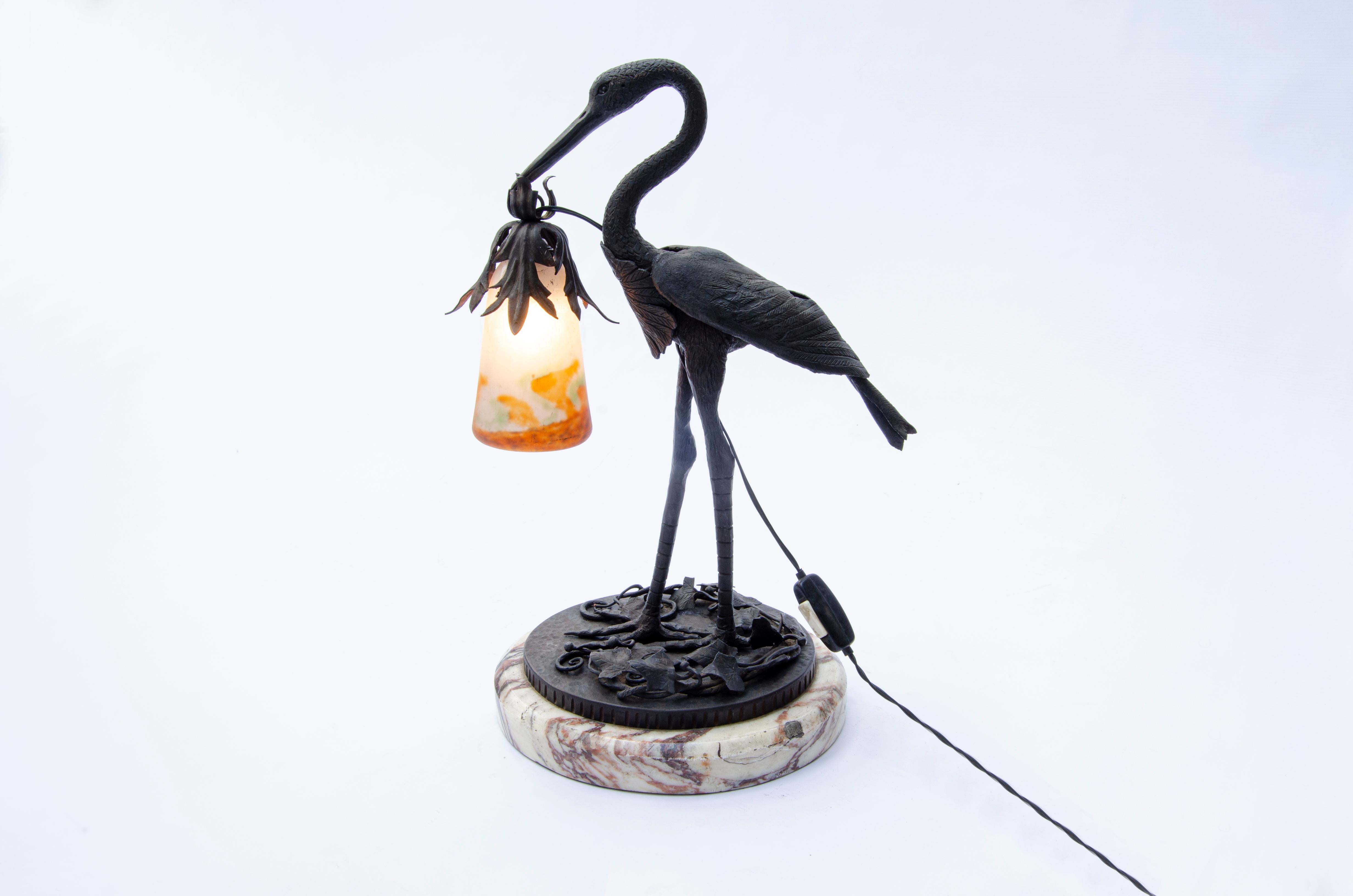 Table lamp with a design of a heron made of iron with a marble base, holding a glass lampshade with its beak. Made by Muller Freres Glass (1858-1959). Signature Muller Fres Luneville.

France, CIRCA 1920.