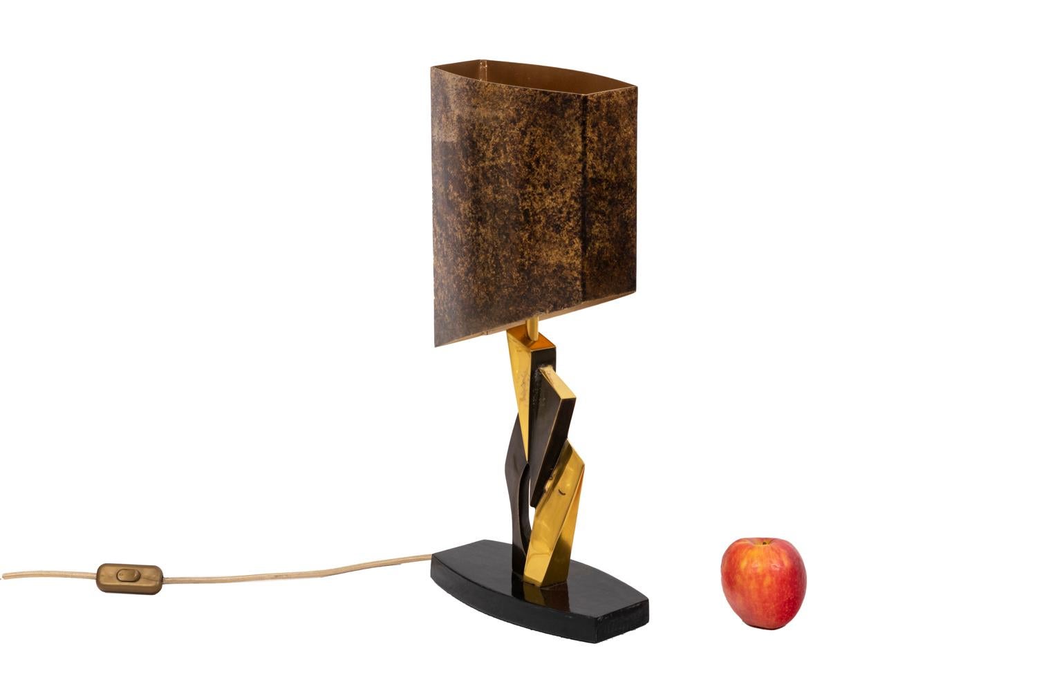 Cubic style lamp in gilt bronze and medal patina. Lampshade in brushed sheet metal and wooden base.

Work realized in the 1970’s.