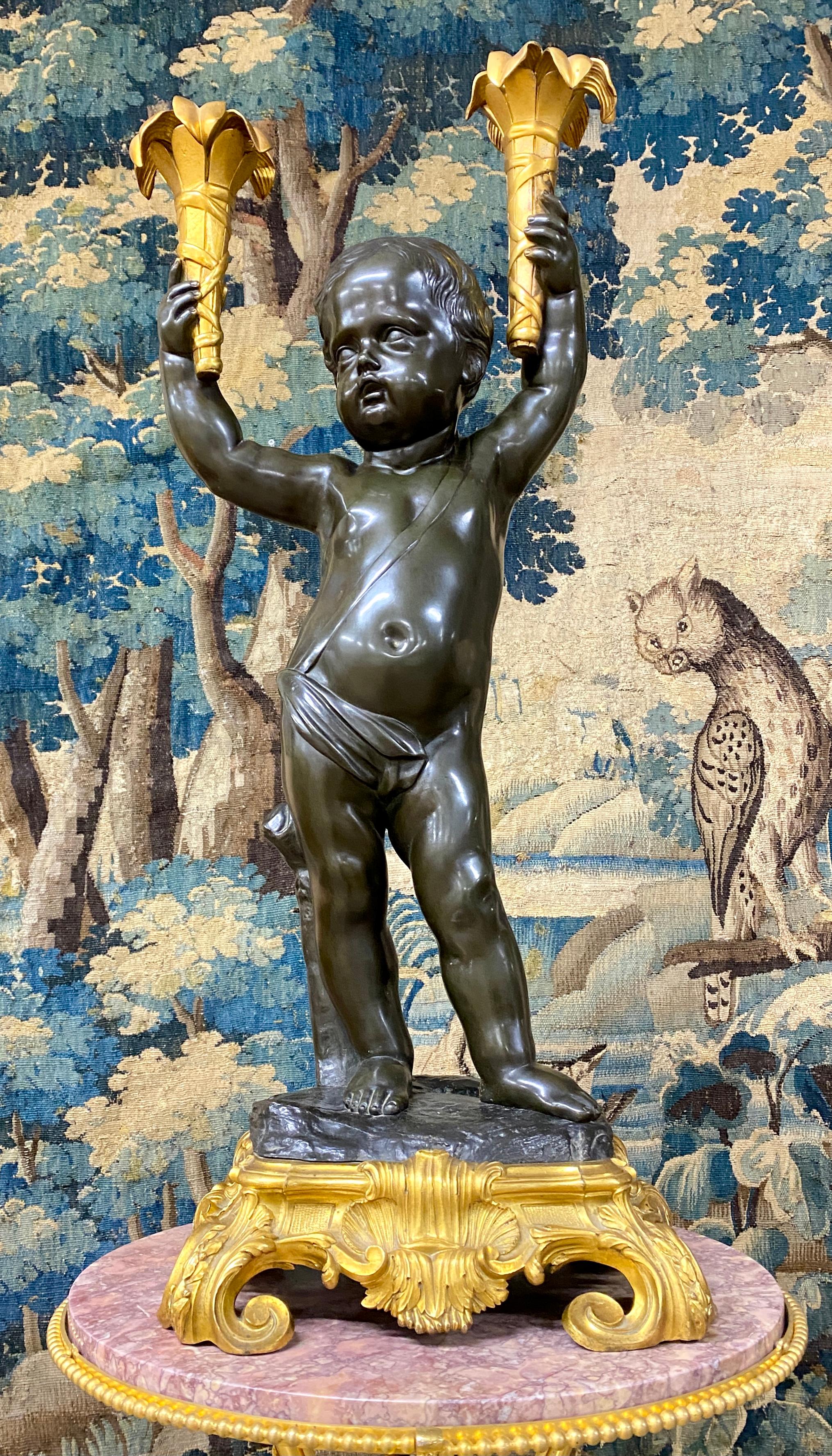 Bronze lamp representing a baby holding two gilt bronze sconces in his hands. It rests on a gilt bronze base also decorated with Louis XV style shells. Very fine workmanship in bronze with brown patina and gilded bronze attributed to Henri Dasson.