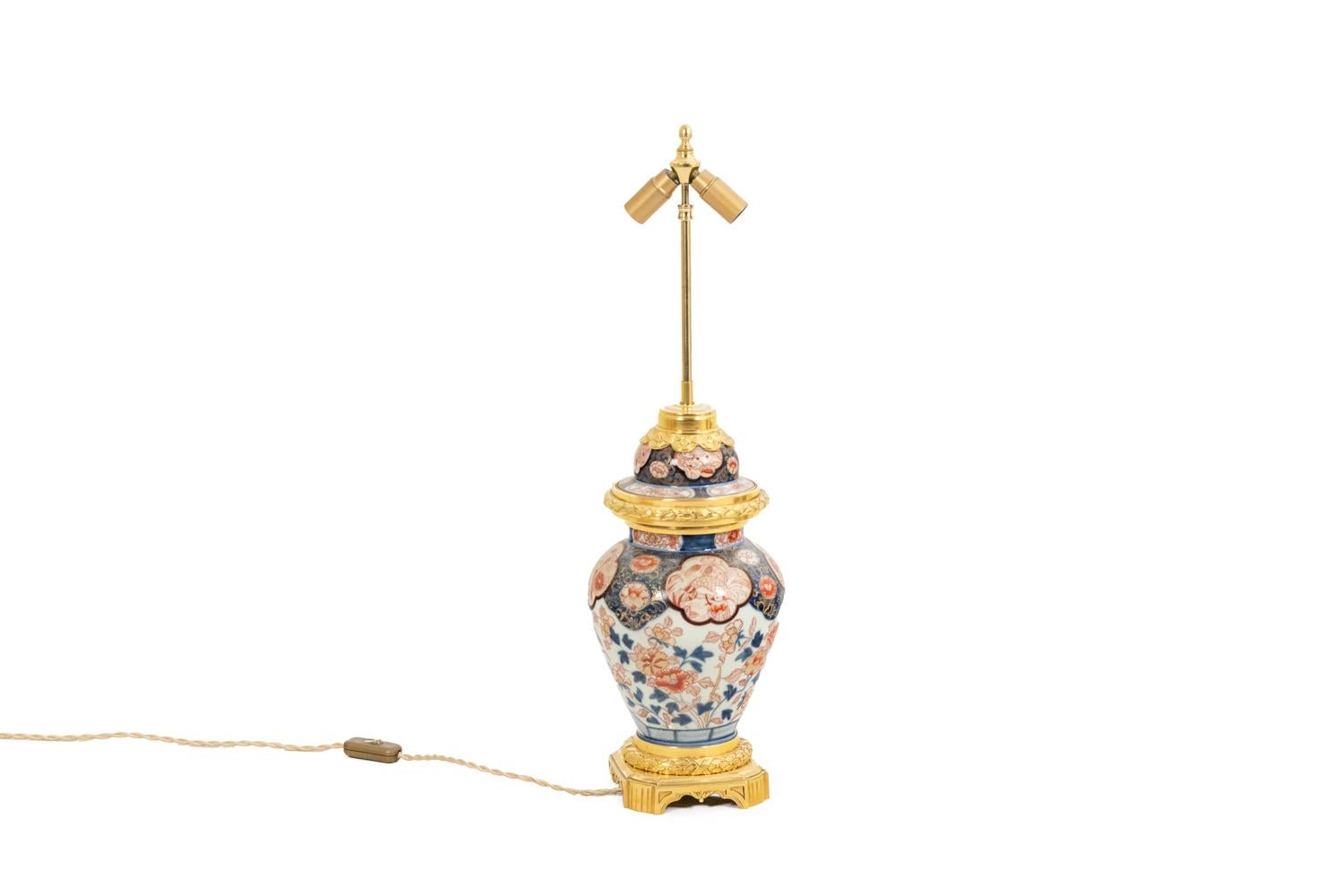 Lamp in Imari porcelain and gilded bronze, adorned with flowers and foliage, in shades of saffron red, cobalt blue and on an ivory white background. Quadripod base, with rudent pattern.

Work realized circa 1880.

New and functional electric