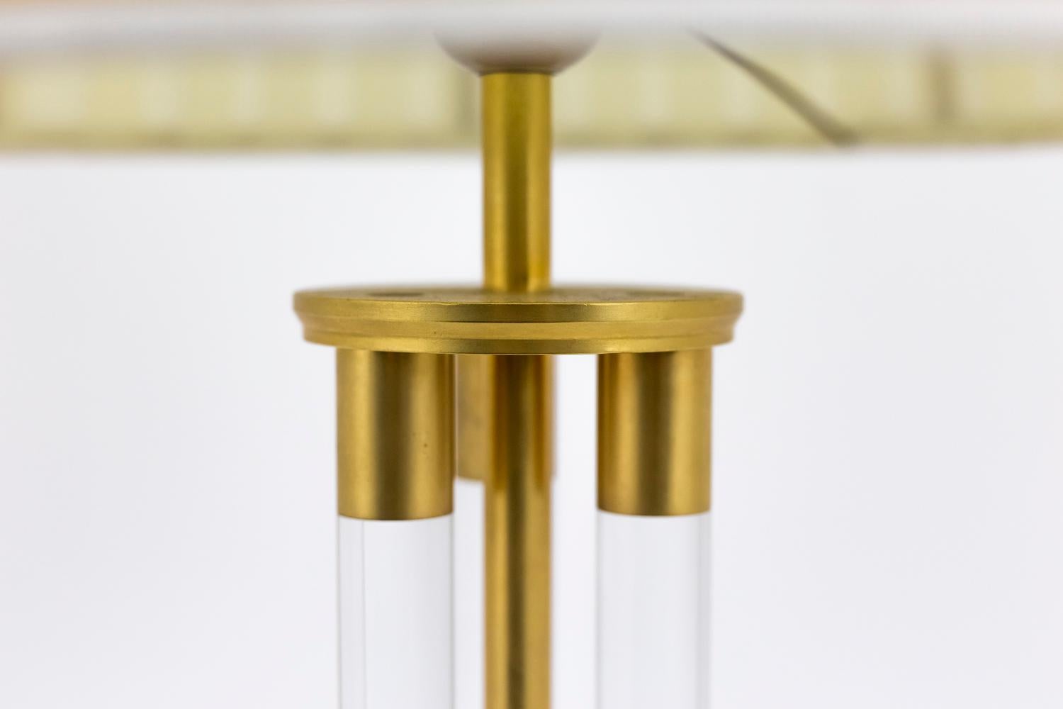 Lamp in Lucite and gilt bronze. Shaft composed of three Lucite tubes holding on the top and bottom by gilt bronze rings and a central gilt bronze stick. Circular base with steps decor.

Work realized in the 1940s.

New and functional electrical