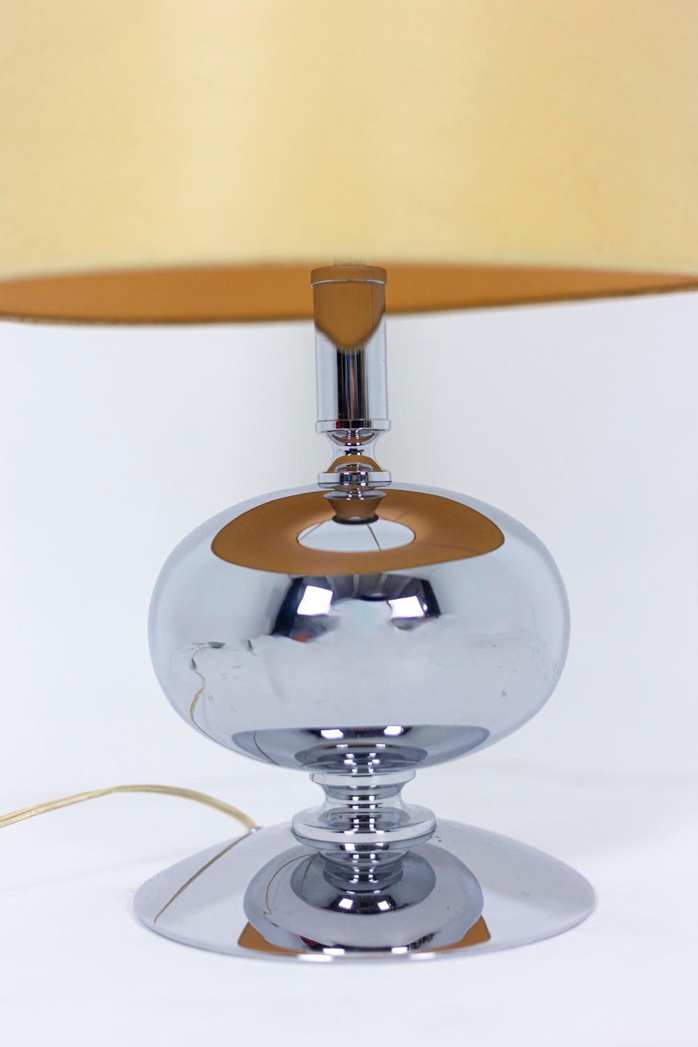 Spherical lamp in polished stainless steel. Circular base supporting a flattened sphere. 

Work realized in the 1970s.