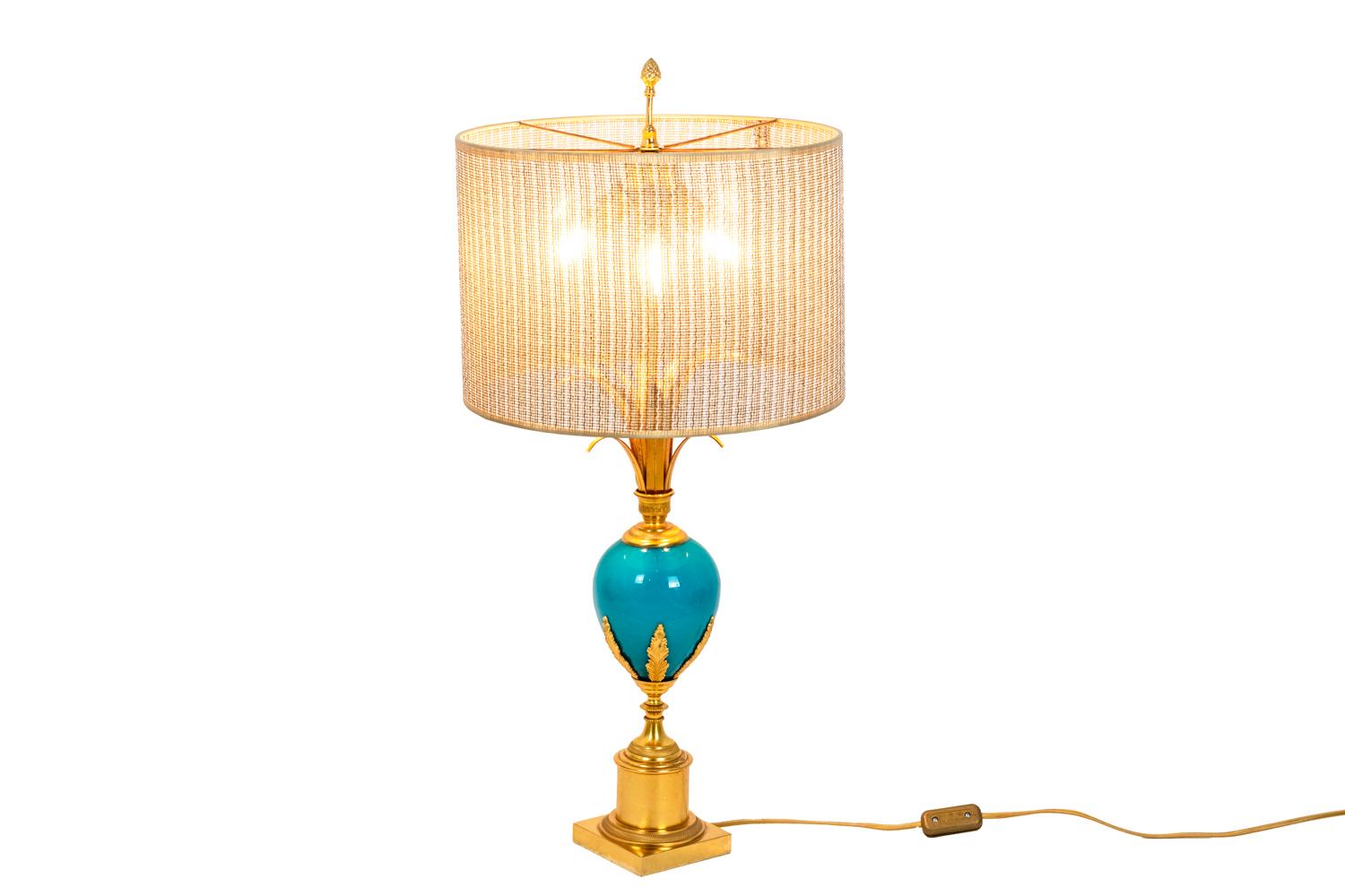 Lamp in turquoise opaline and gilt bronze with an egg shape shaft topped by reeds leaves and finished by acanthus leaves. Lamp topped by a pine cone and finished by a brushed bronze cylinder decorated with swirls. Square base.

Work realized in