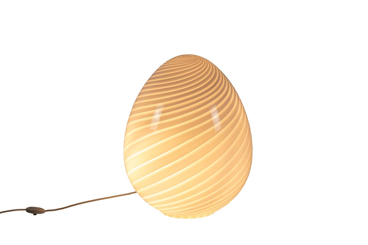 Egg-shaped lamp in white striped Murano glass.

Work realized in the 1970s.

Functional electrical system.

  