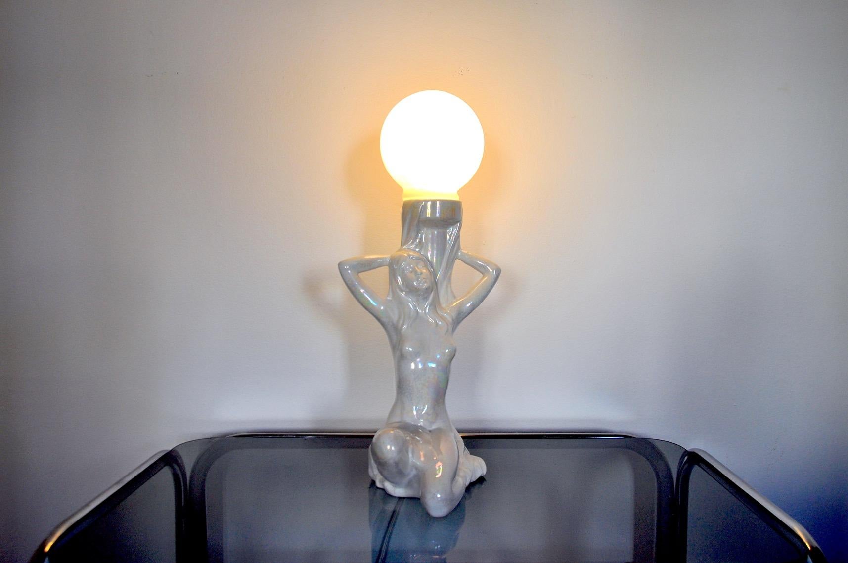 Very pretty table lamp representing a naked woman dating from the 70s. The lamp is made up of a black ceramic sculpture and a white opaline globe. Lamp that will bring a real vintage and decorative touch to your interior. Electricity checked,