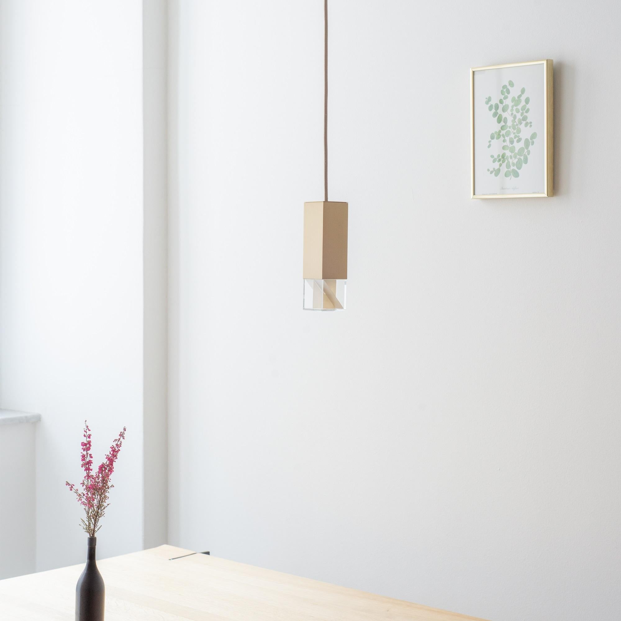 This refined pendant lamp has a simple design that emphasizes its contemporary style and the prized materials used to craft it. The square ceiling plate (5 x 5 x 5cm) and the rectangular shade are handmade of satin-finished brass, connected by a