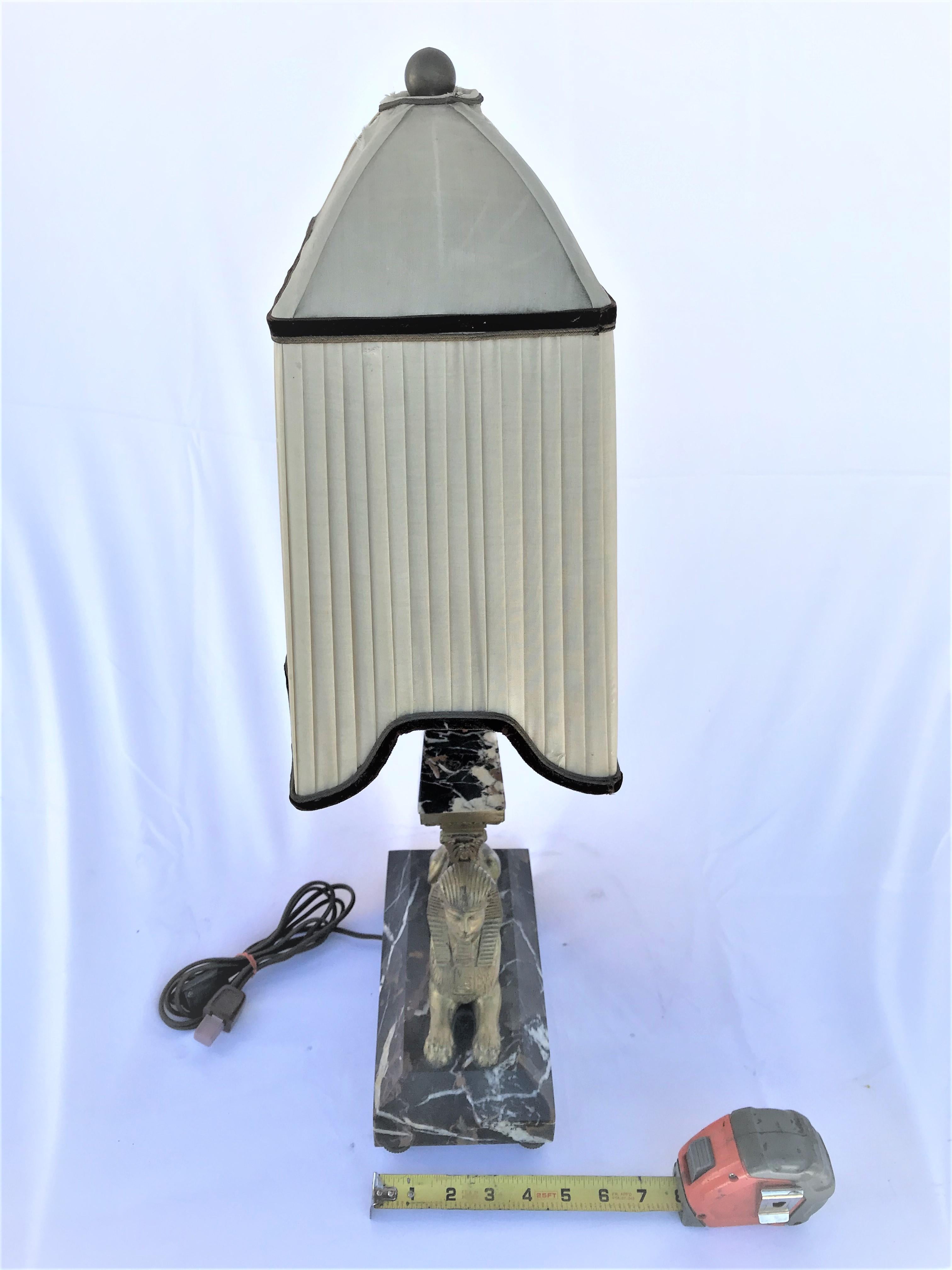 Sphynx lamp cast in bronze with doré gold finish. Has original linen shade. With marble base and obelisk post. Shade is in the shape of a tent with black borders. Small damage to shade on top. Really looks great when lit up at night. This item