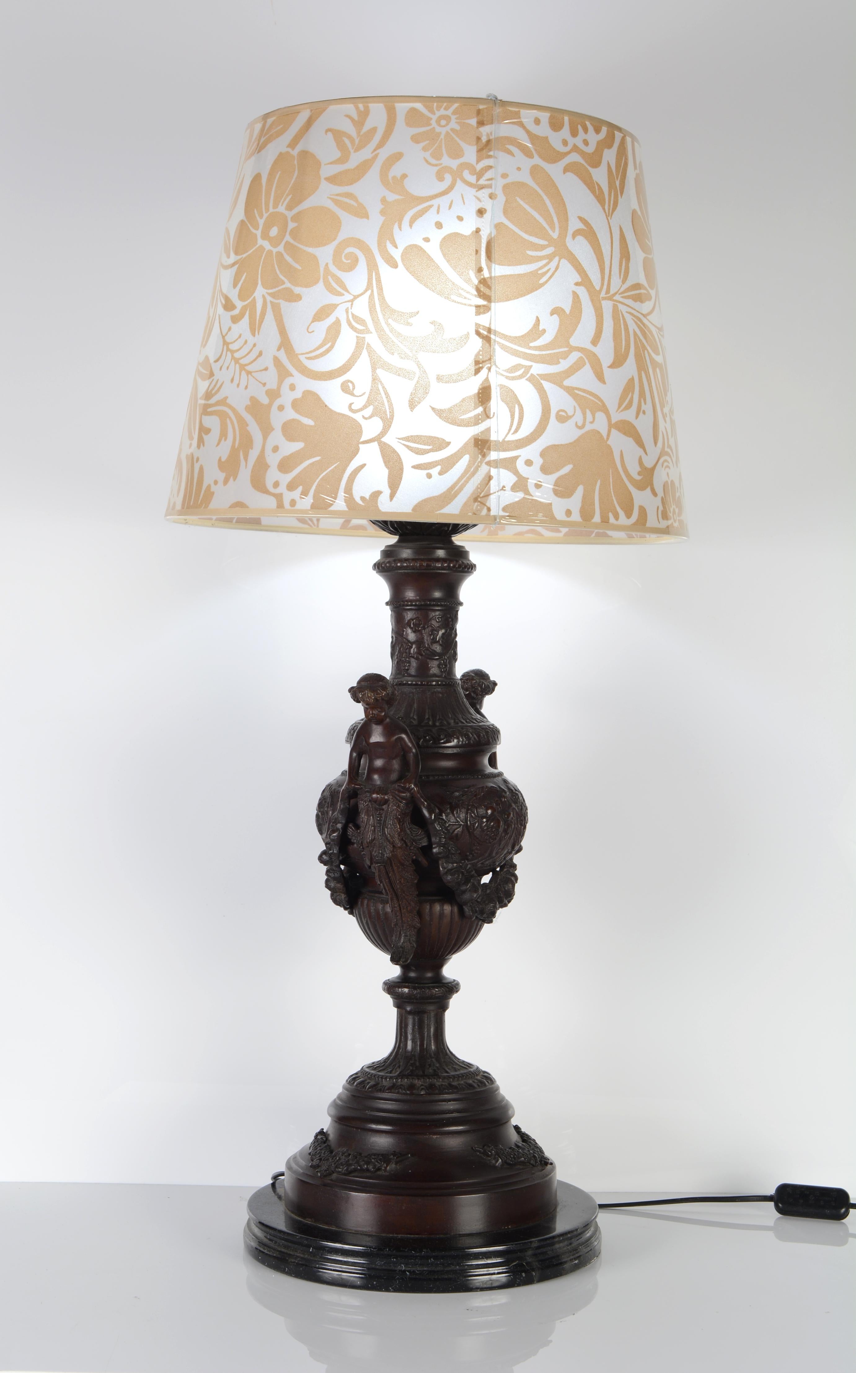 Lamp base with vase and grotesques. Patinated bronze and marble base.
Without display
The round base enhances the lamp base, consisting of a vase decorated with gallons, branches, grapes and vegetable scrolls. On the sides, two grotesques made up