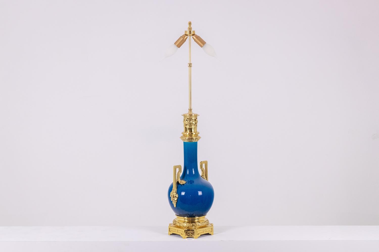 Louis XVI style lamp in blue porcelain and gilded bronze, with its handles ending in leaves, the top of the frame decorated with a gadroon and an openwork gallery decorated with bunches of grapes, the base decorated with ‘one garlands and four