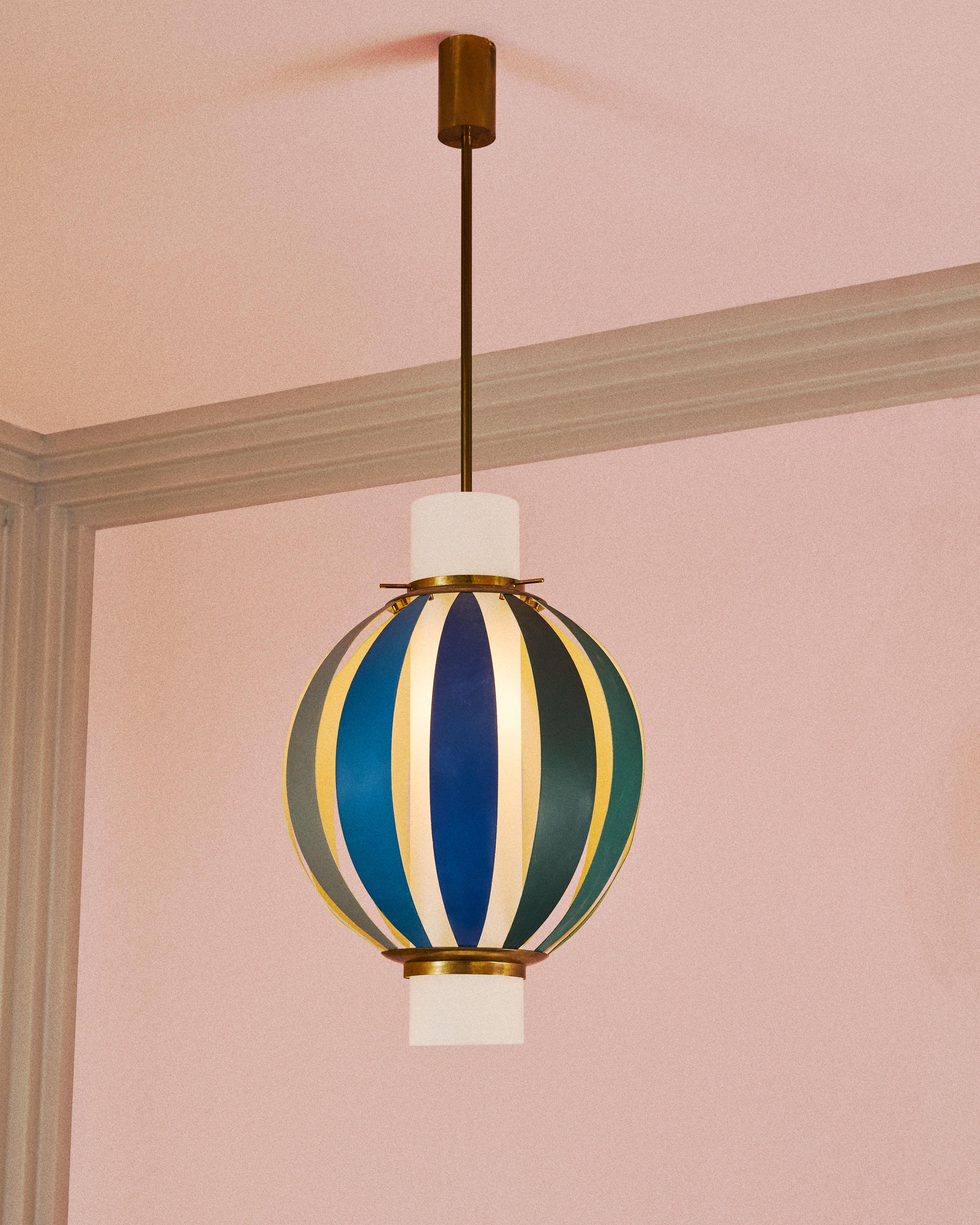 Lampada a sospensione Arcobaleno, mod. 12522, composta da elementi in alluminio verniciato dai toni vivaci, dettagli in ottone lucido e diffusore in vetro opalino bianco. Design di Angelo Lelii per Arredoluce, 1956.
Questa lampada esprime una delle