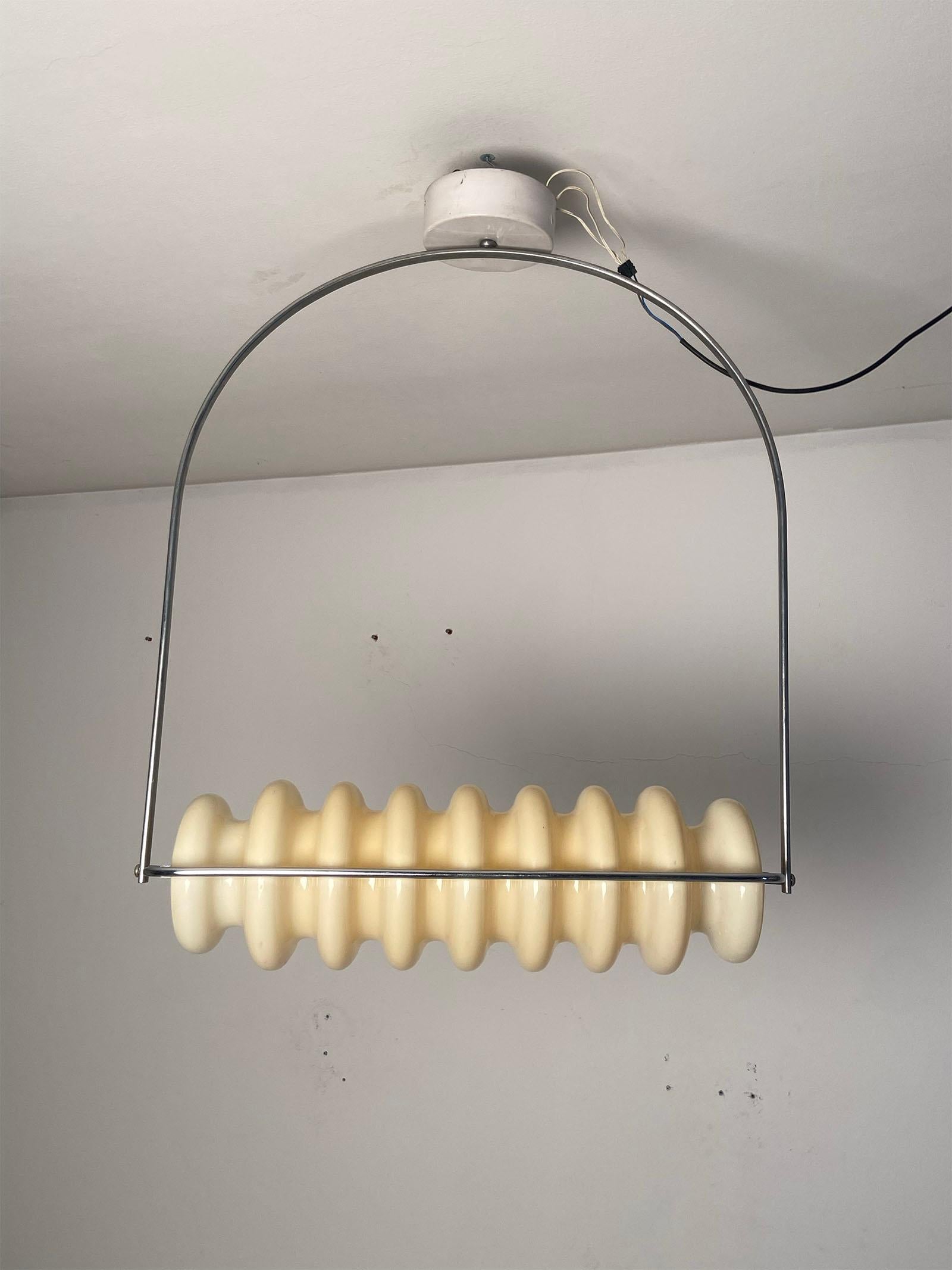 Lampada da soffitto disegnata da Ettore Sottsass e prodotta da Poltronova intorno al 1970. Il paralume in materiale plastico è fissato ad un tubo in ottone cromato. La sua forma originale ma allo stesso tempo elegante rendono questa lampada da