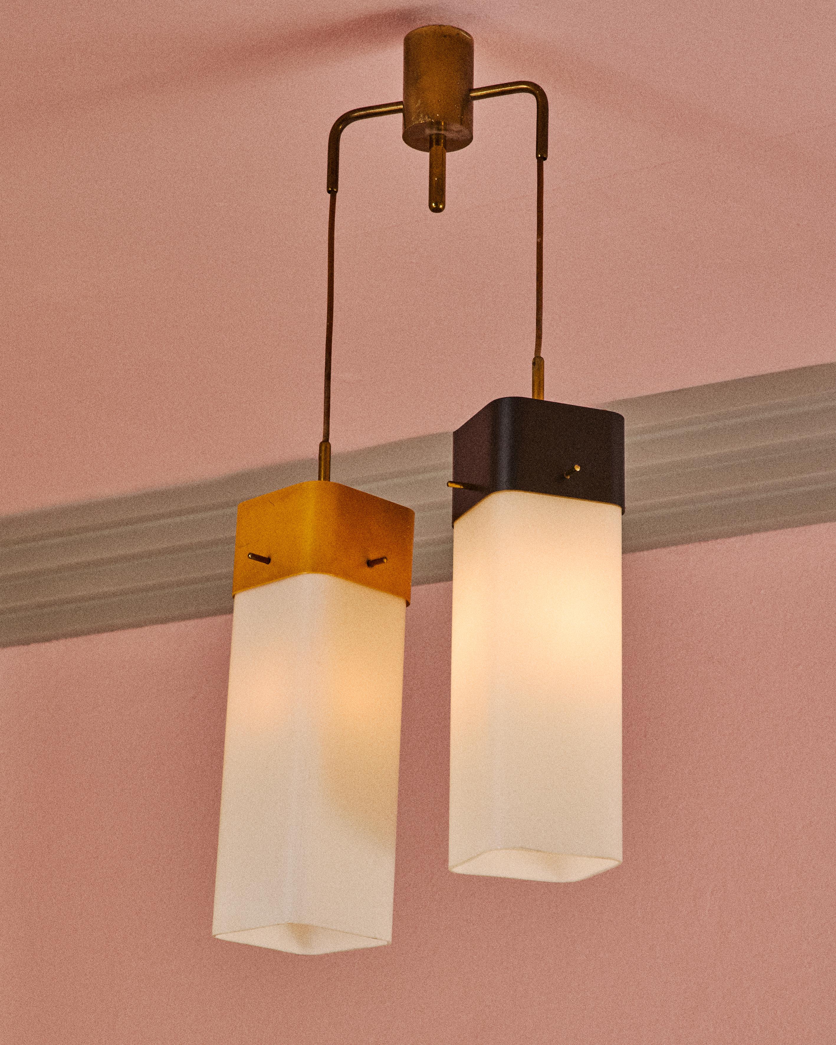 Lampada pendente costituita da due diffusori in vetro opalino bianco sostenuti da supporti in ottone verniciato di differente colore e da una struttura in ottone lucido. Disegno di Angelo Lelii per Arredoluce, Italia, anno 1957. Questo modello