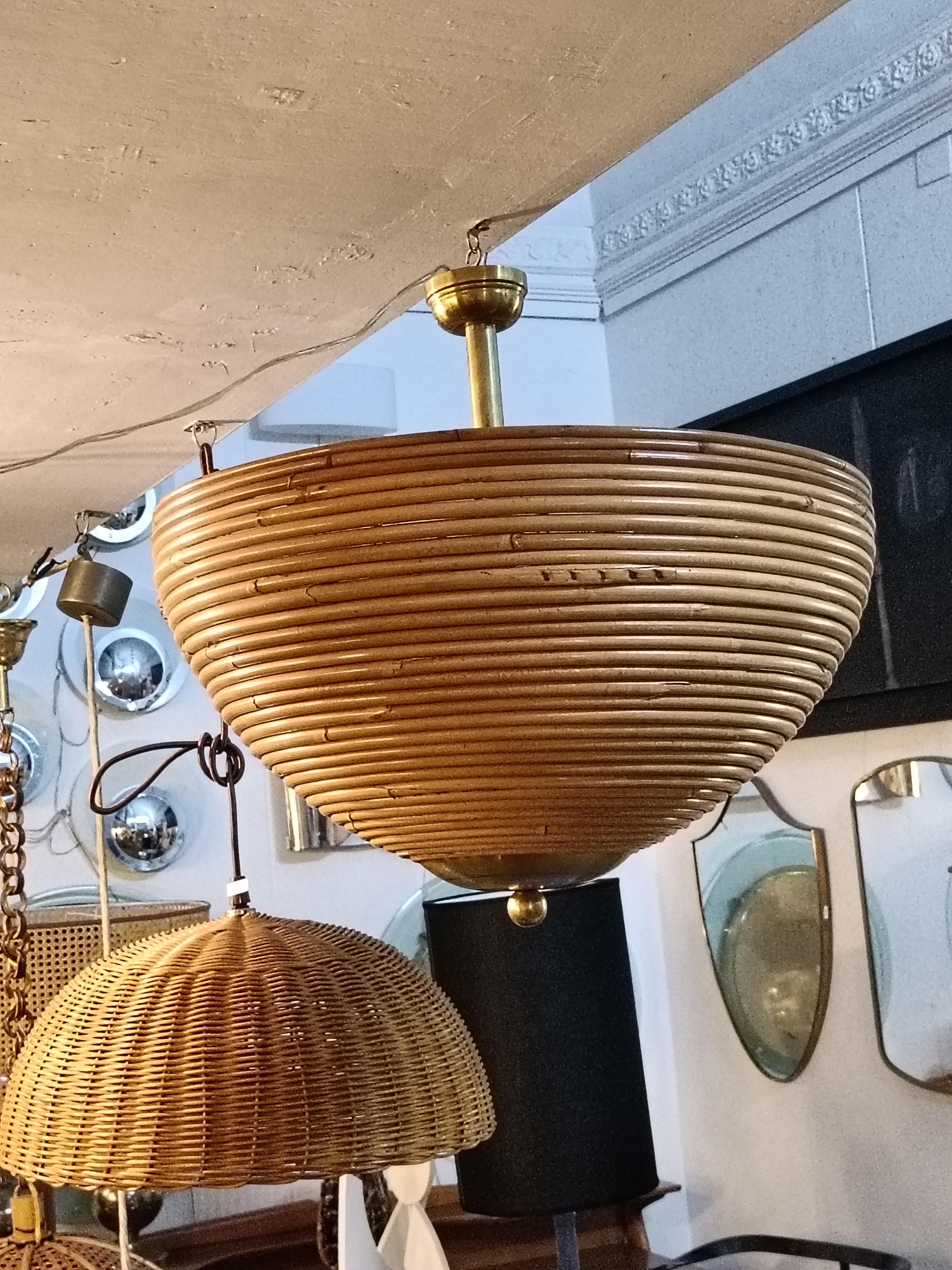 Lampada a sospensione in canna di rattan artigianale nello stile Gabriella Crespi a forma di cupola con dettagli in ottone degli anni '70 dal design circolare. Questa lampada a sospensione ha un paralume a campana che pende da un tubolare in ottone