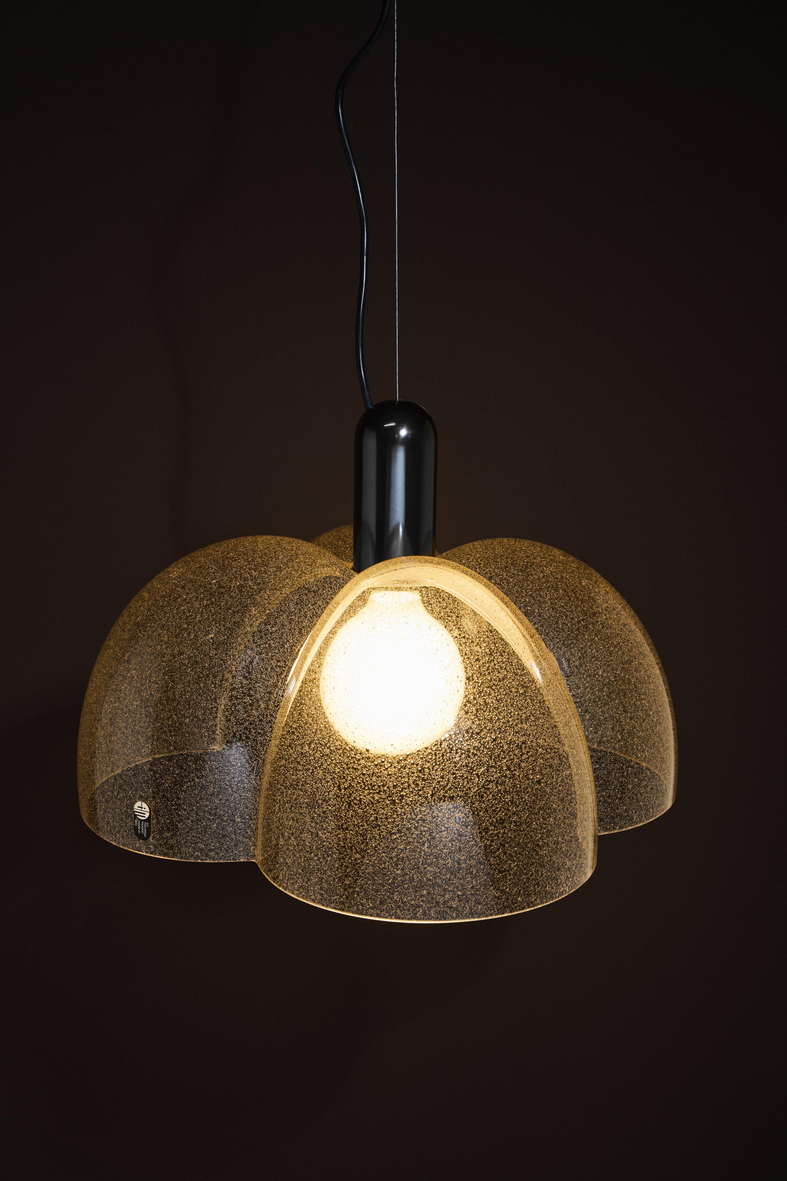 Lampada a sospensione LS111 a quattro lobi in vetro di Murano pulegoso fumé, disegnata da Carlo Nason per A.V. Mazzega, Italia. Anno 1970 ca. 
Carlo Nason (nato nel 1935 a Murano, Venezia) è un designer e maestro vetraio italiano, noto per le sue