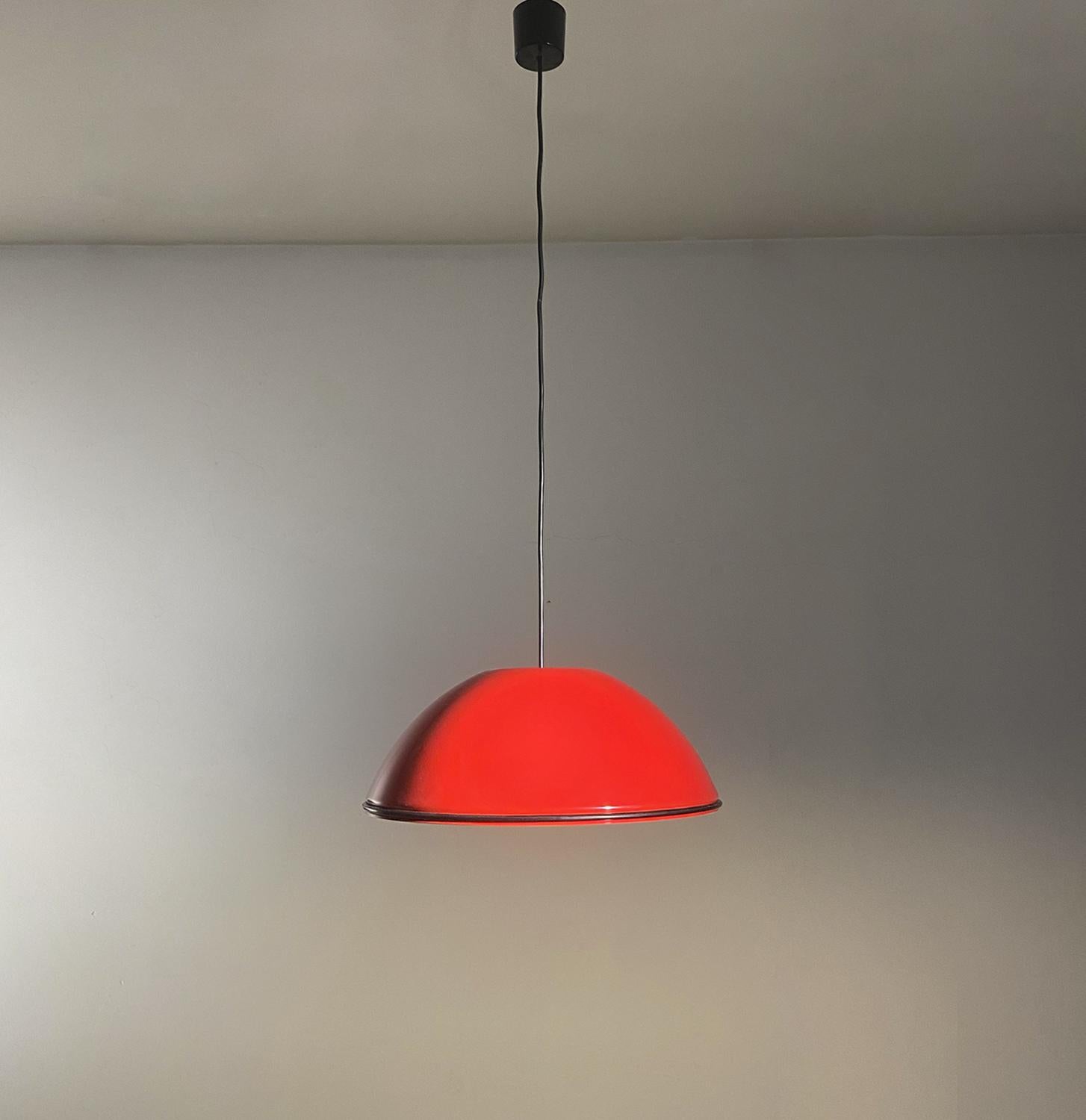 Lampada a sospensione Relemme 75 disegnata da Achille Castiglioni e prodotta da Flos nel 1962. La lampada presenta un paralume semi circolare in metallo lucidato esternamente in rosso e interamente in bianco. Attorno al diffusore è presente un