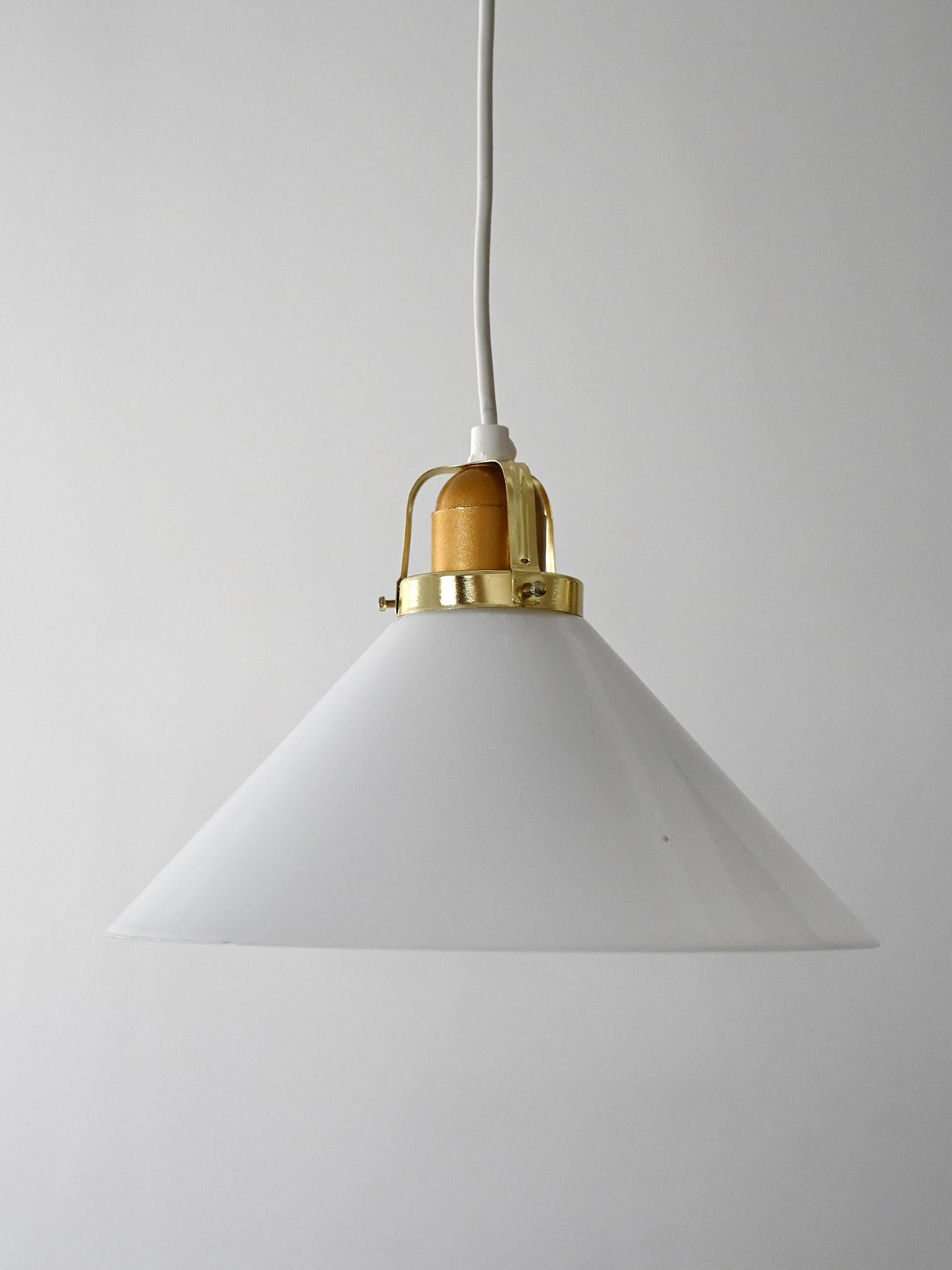 Lámpara vintage de cristal opalino con grifería de latón y madera torneada. Producción escandinava de los años cincuenta.

Lámpara colgante escandinava de los años 50 con pantalla cónica de cristal opalino blanco. La parte superior se complementa