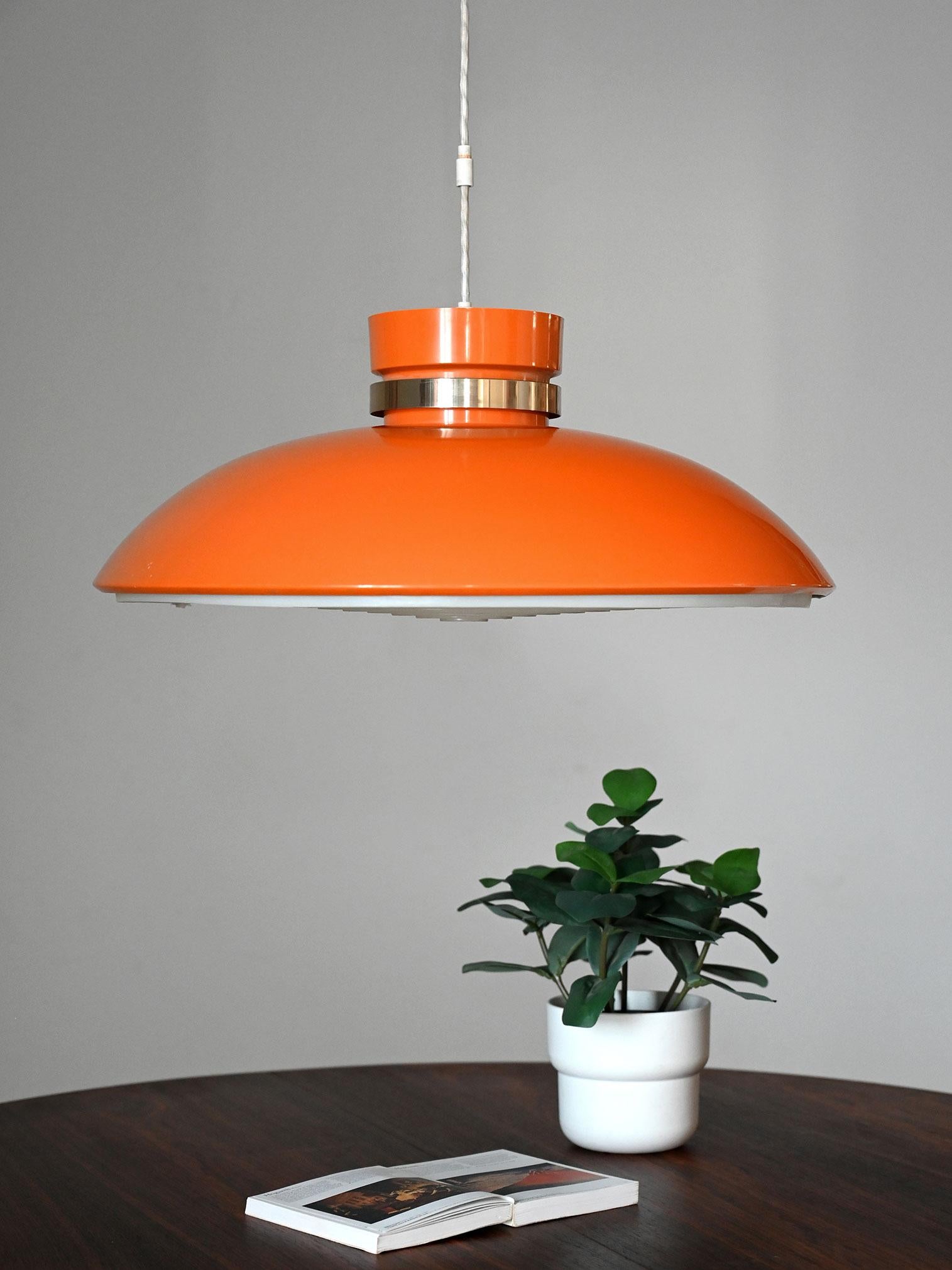 Lampada a sospensione anni ’60 in plastica arancio con inserto anulare in metallo e diffusore sottostante integrato a cerchi concentrici. Geometria a semisfera dal carattere pop, luce morbida e omogenea.

Lampada a sospensione scandinava anni ’60 in