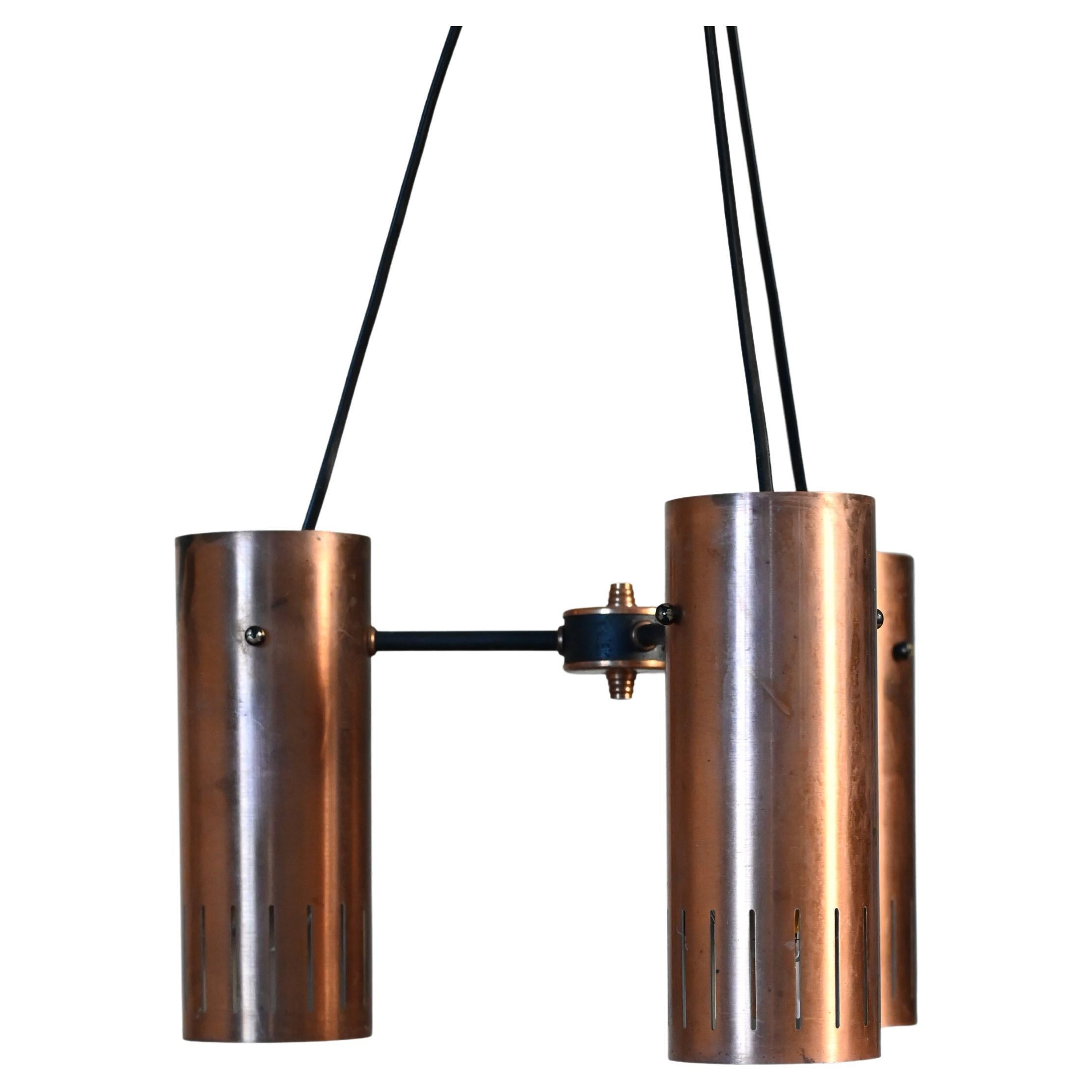 Sospensione scandinava anni ’50/’60 in rame con tre punti luce. Cilindri traforati che diffondono una luce calda; struttura centrale in metallo cromato nero con dettagli in rame.

Sospensione scandinava anni ’50/’60 composta da tre corpi cilindrici