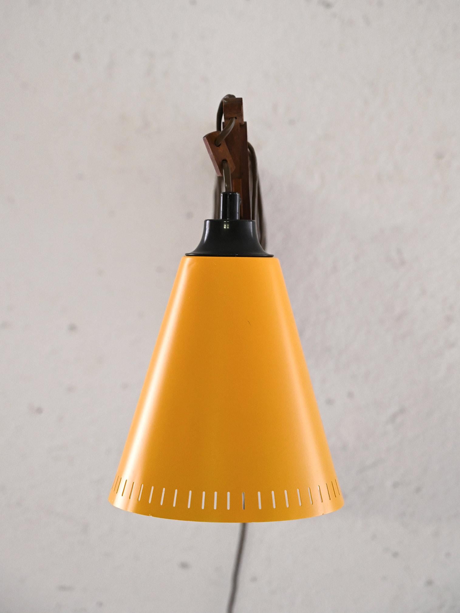 Vintage wall lamp with extendable arm (maximum length 130cm) made of wood and cone-shaped yellow metal shade.

The wooden frame, with its accordion mechanism, allows the extension of the lamp to be adjusted as needed. 
Good conditions. Potrebbe