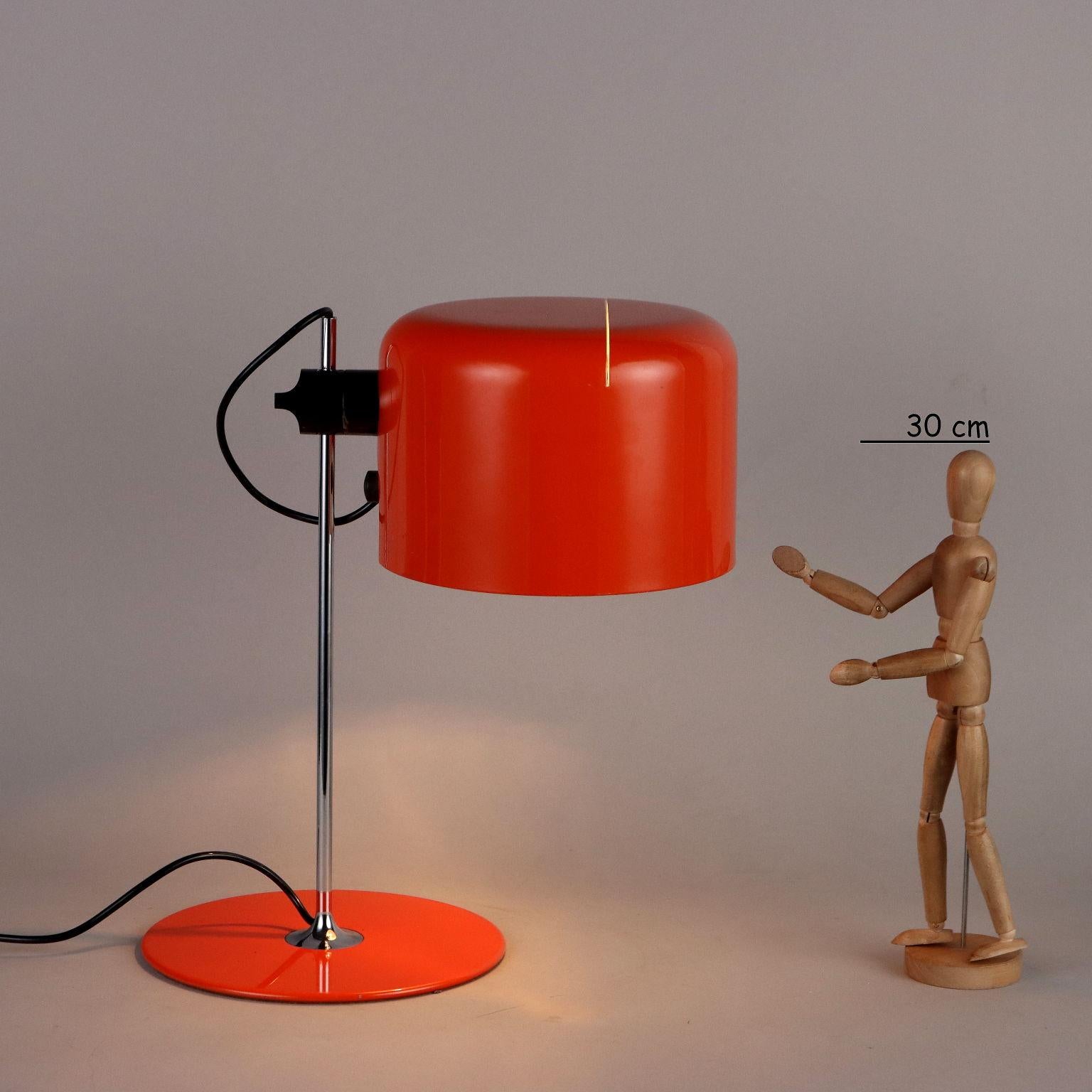 Lampada da tavolo disegnata da Joe Colombo nel 1967 presenta una base circolare in metallo laccato, stelo verticale in metallo e diffusore orientabile e regolabile in altezza in alluminio laccato. La presentiamo nella versione in arancione in