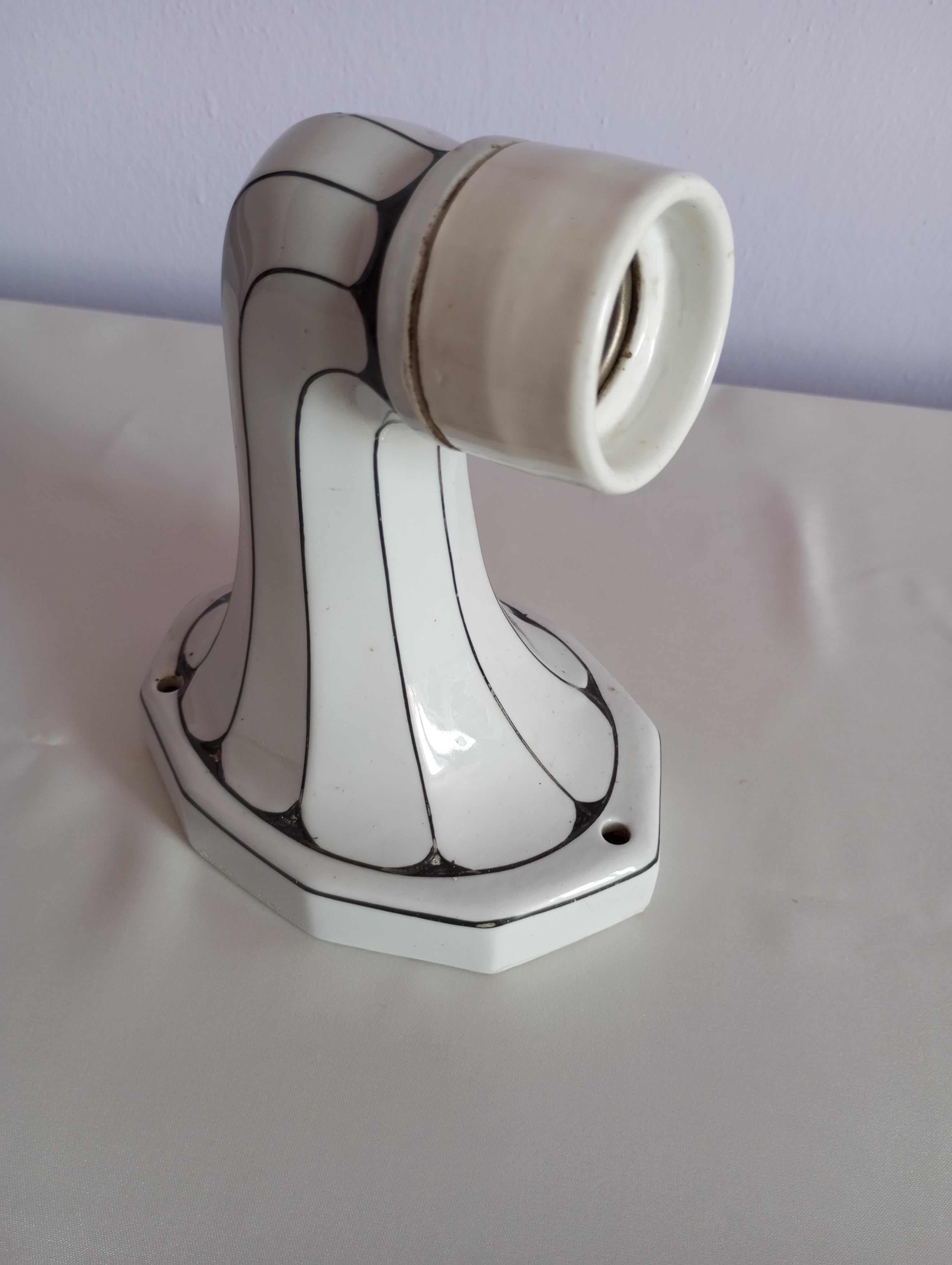 Questa applique da parete, realizzata negli anni '60, rappresenta un elegante esempio di stile Art Nouveau, con il suo braccio in porcellana smaltata caratterizzato da una raffinata combinazione di bianco e nero. L'armonia dei colori, unita alla