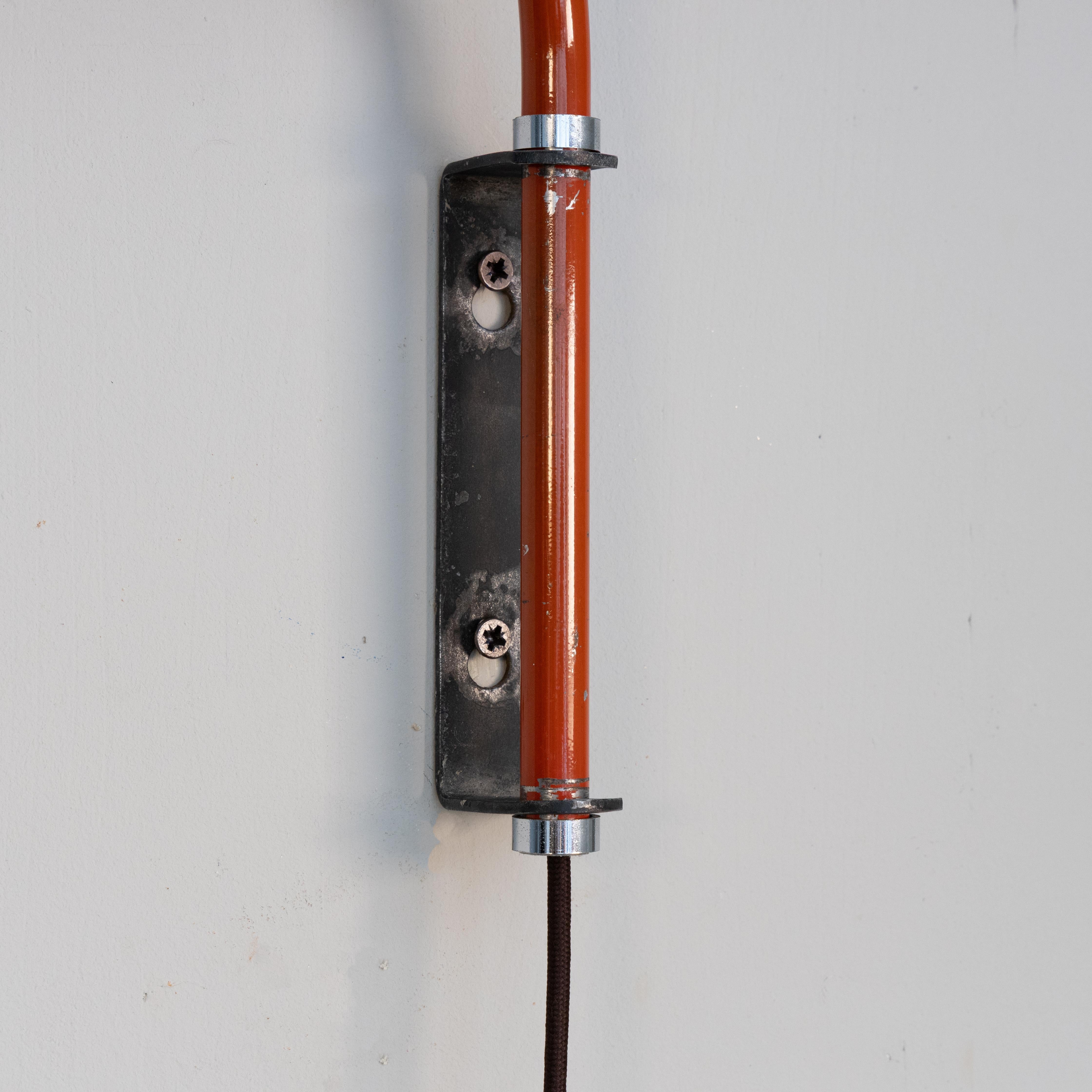 Lampada da parete estensibile progettata da Heinrich-Siegfried Bormann nel 1970. Struttura in metallo verniciato rosso con braccio snodabile ed estensibile, riflettore orientabile. Versione rossa. Design funzionale e meccanismo regolabile.