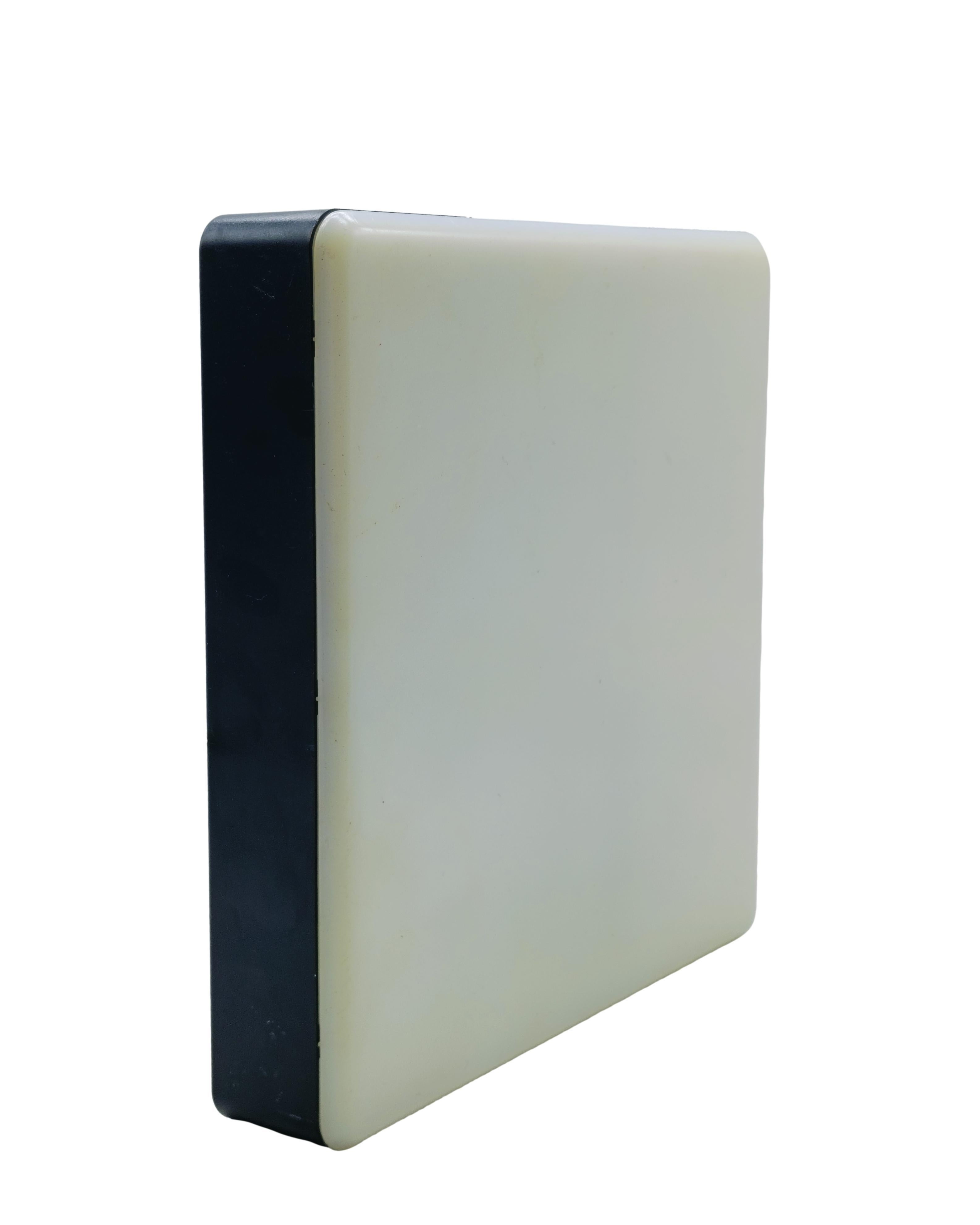 Moderna lampada da parete degli anni 70 di forma quadrata, struttura in metallo nero e acrilico bianco.