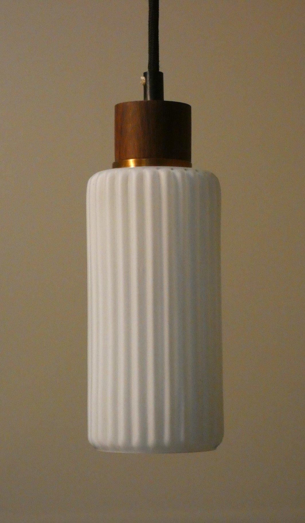 Rara ed estremamente elegante lampada a sospensione in vetro opalino, teak e ottone della metà del secolo scorso, risalente agli anni '50 e che ricorda le lampade Stilnovo e Arredoluce dello stesso periodo.

Altezza massima: 130 cm
Diametro: 10 cm