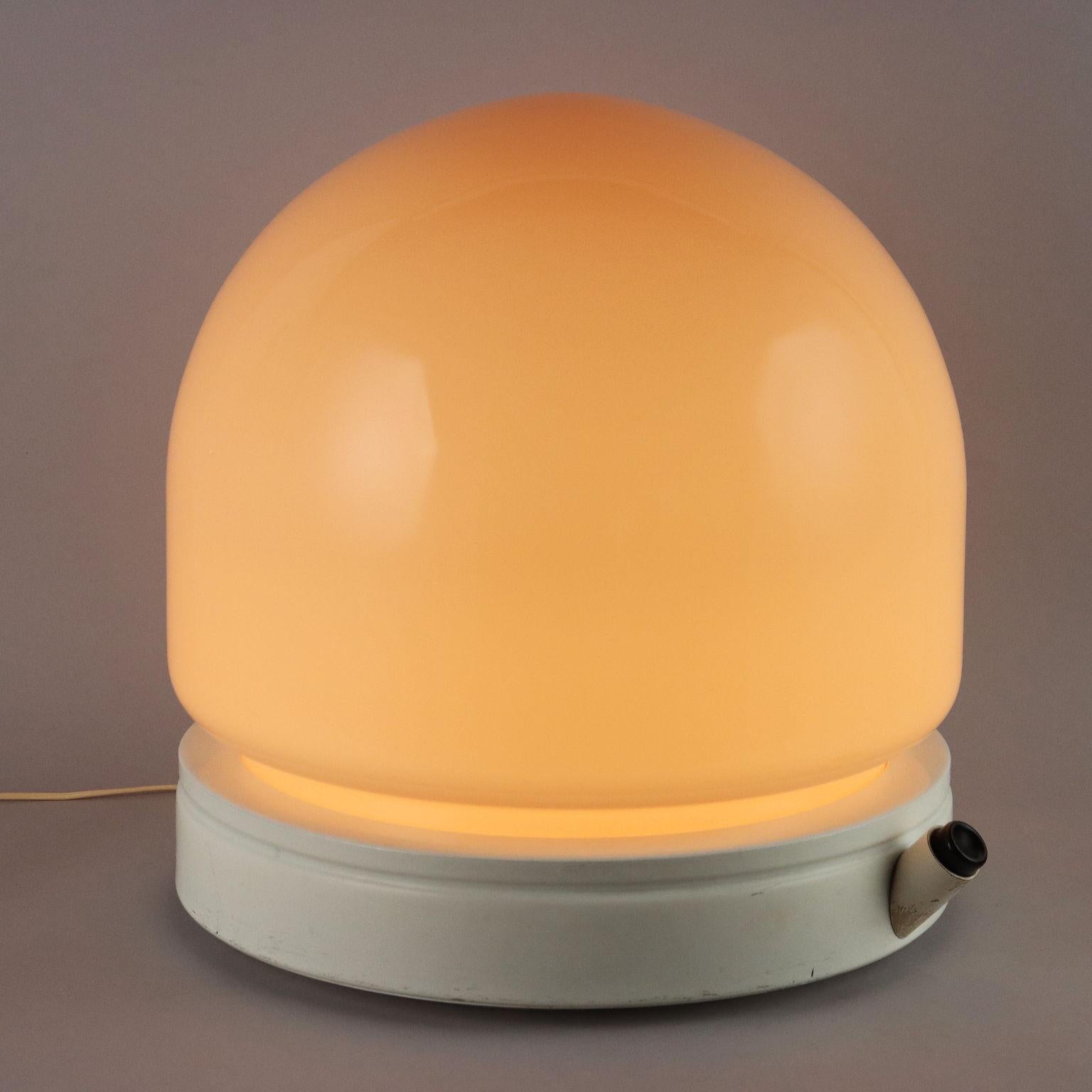 Lampada da tavolo vintage di produzione Stilnovo con base in alluminio smaltato bianco, grande diffusore in vetro color salmone, accensione a pulsante. 