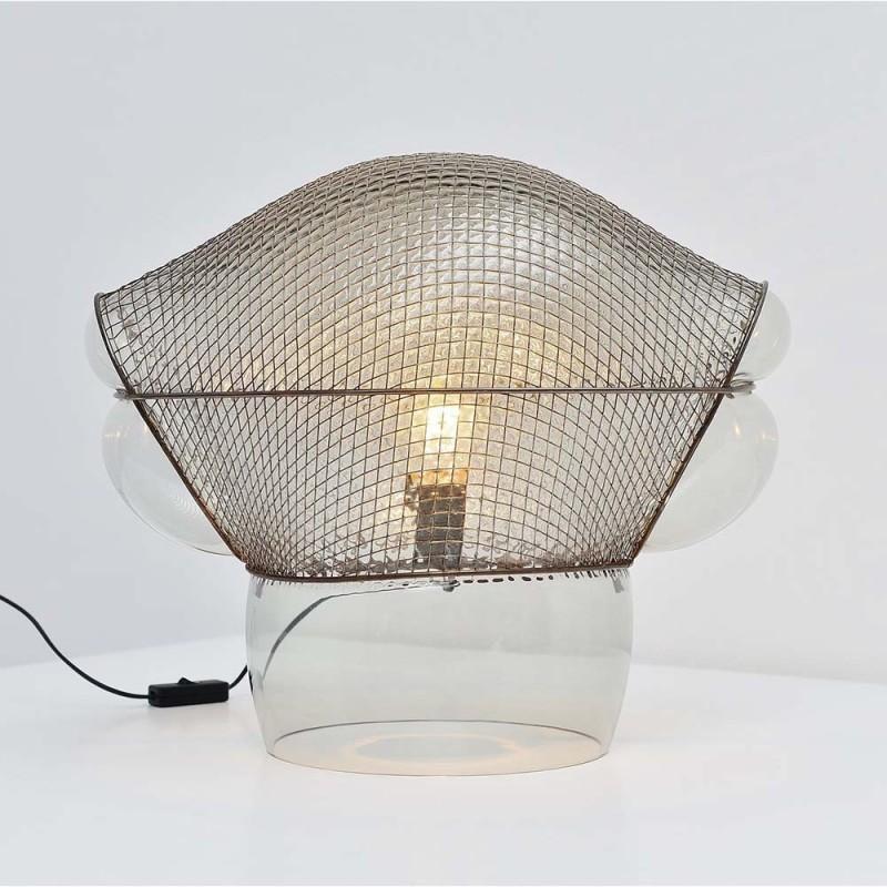 Patroclo model table lamp from the manufacturer Artemide, designed by Gae Aulenti in the 1970s. 
The structure of the lamp body is made of transparent blown glass with one part of the diffuser covered by a metal armature in the shape of an irregular