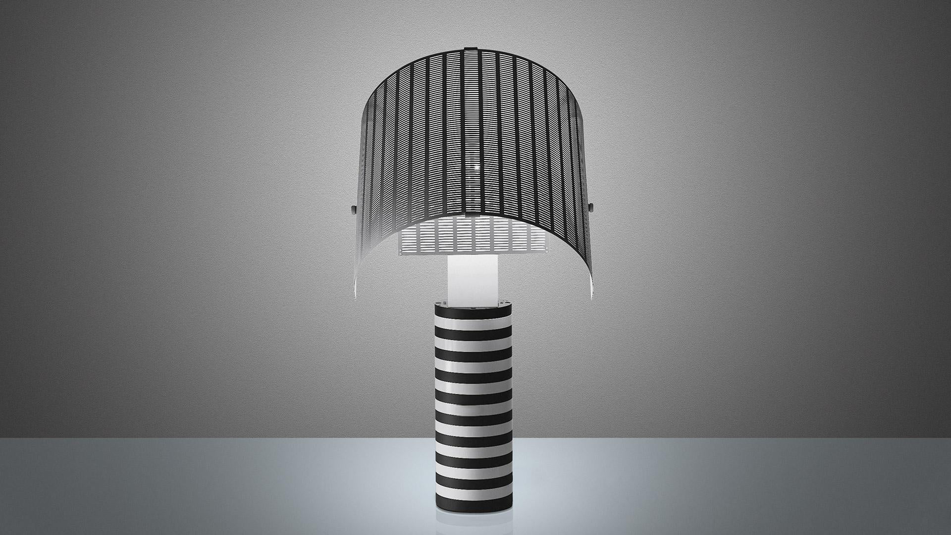 Lámpara de mesa modelo Shogun del fabricante Artemide, diseñada por Mario Botta en la década de 1970. 
La luminaria consta de un vástago metálico pintado en blanco y negro y difusores orientables de chapa de acero perforada pintada en blanco.
La