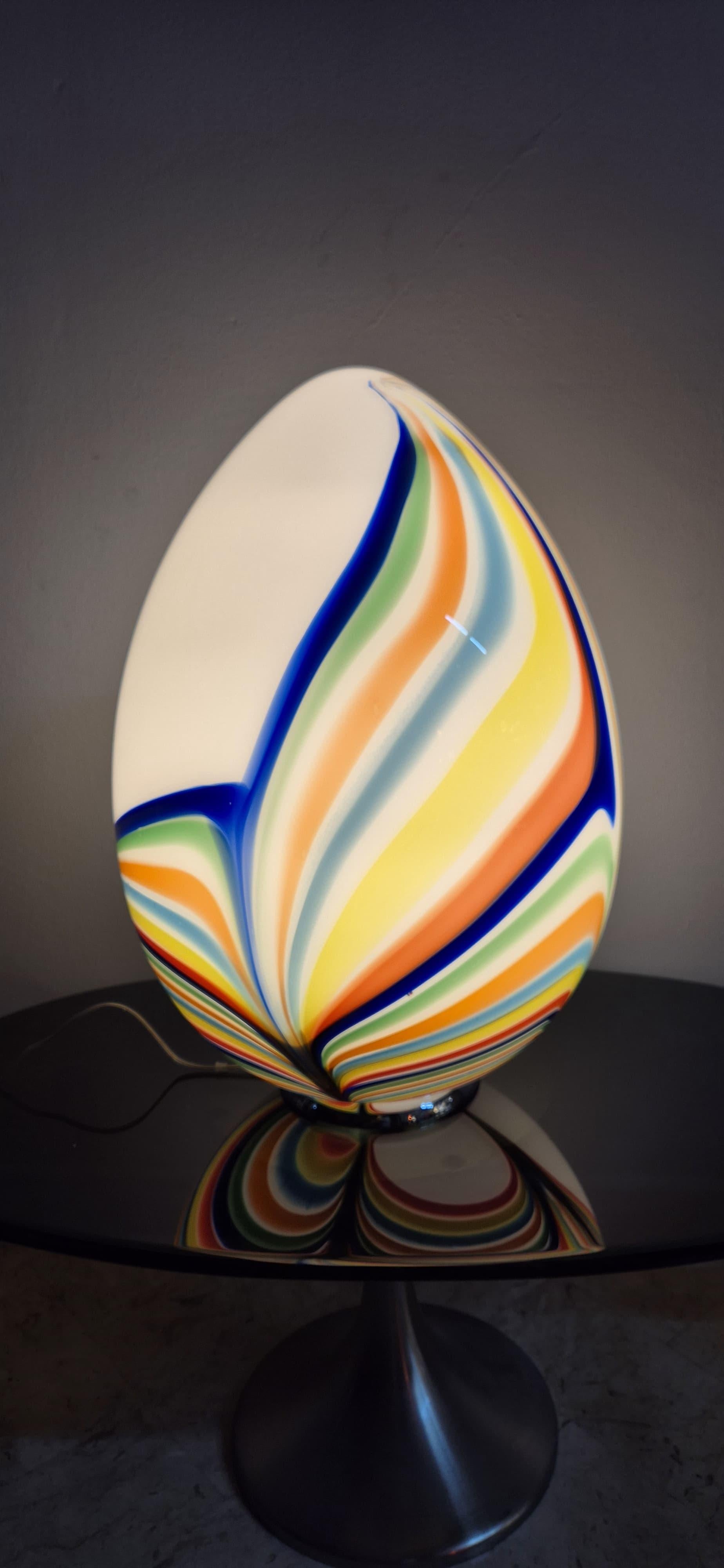 Hermosa y distintiva lámpara de mesa Egg de cristal de Murano. Base de metal, la lámpara tiene forma de huevo y está hecha de cristal de Murano blanco con varillas multicolores fundidas para formar un patrón de colores.