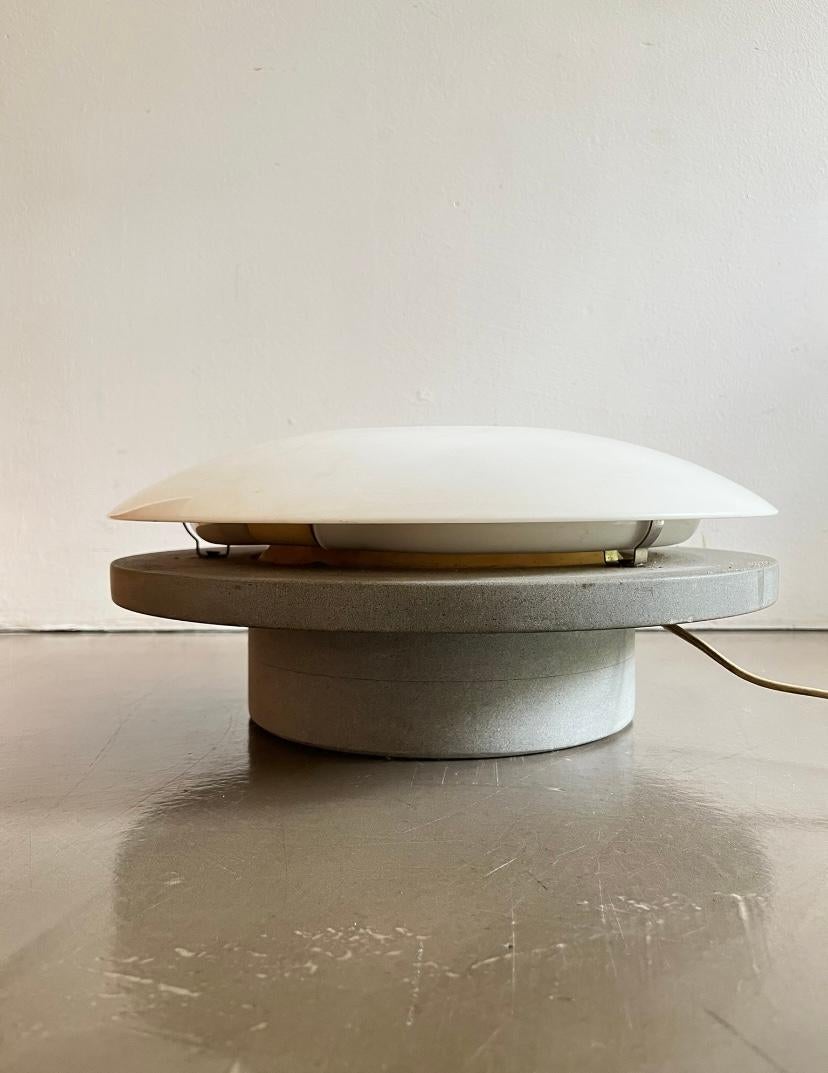 Lampada da tavolo in cemento e marmo, fine anni '70 / inizio '80
Lampada scultorea composta da una solida base in cemento lisciato e un top in pregiato marmo bianco di Carrara, lavorato con cura e precisione. Una volta accesa, la lampada evoca