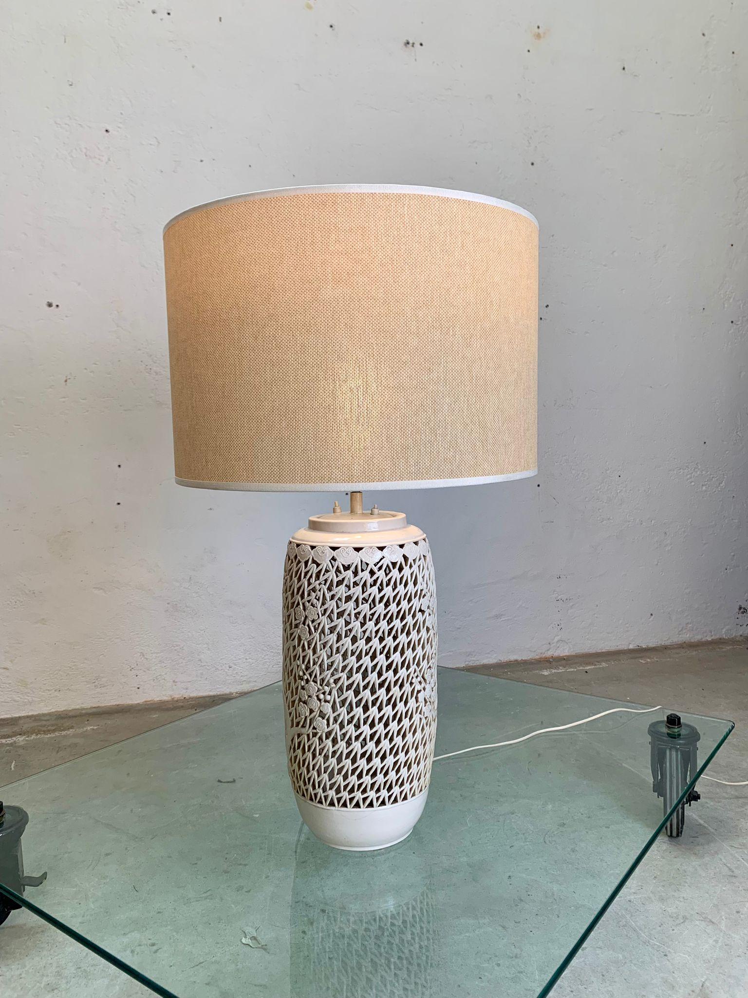 Glazed ceramic table lamp and fabric shade, 1960, italy.
Glazed ceramic table lamp in white, body pierced with geometric and floral motifs. Base with polished finish. Large fabric lampshade (diameter 54 cm), metal frame. Overall height 91 cm.