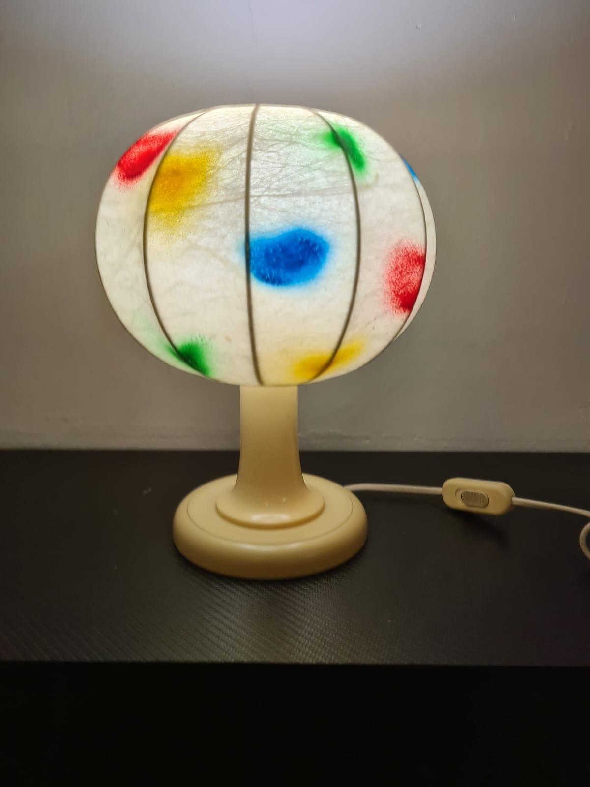 Lampe de table en Cocoon Crèaation.

Abat-Jour réalisé en cocon et décoré de bombes de peinture multicolores.

Le cocon est un matériau intéressant qui a été exporté en Italie dans les années 1960.

Il s'agit d'un matériau plastique qui est