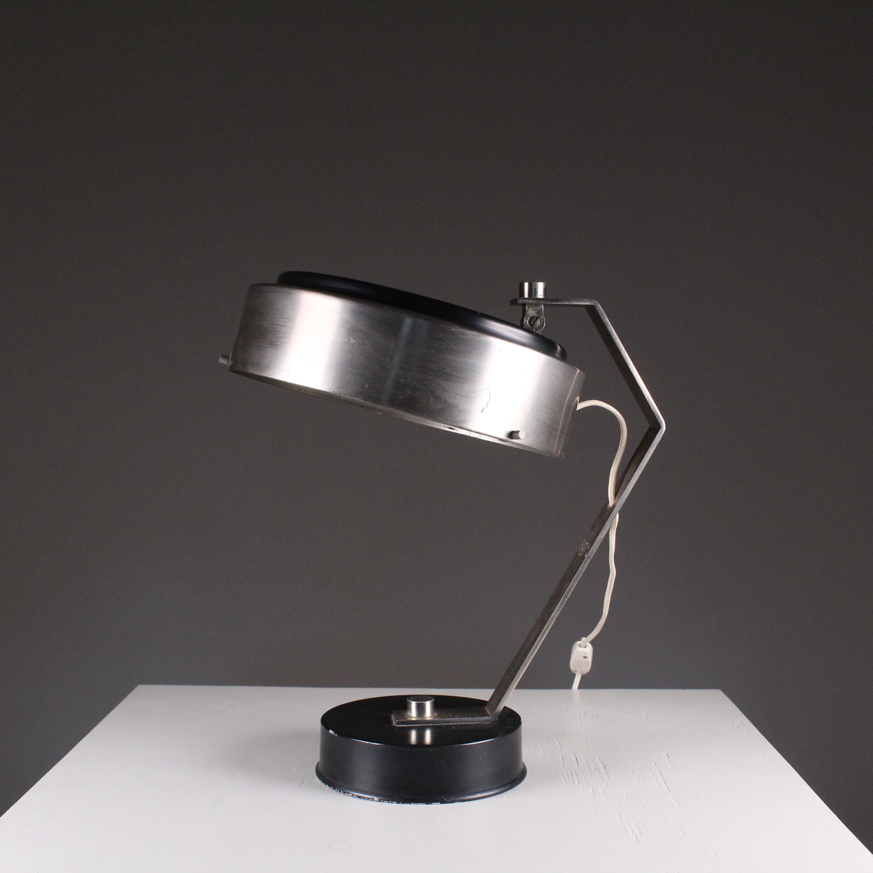 A 1960s Space Age style metal table lamp would embody the spirit of the space age through a futuristic and futuristic design. Featuring bold shapes, clean lines and shiny metallic materials, this lamp would be inspired by the vision of technological
