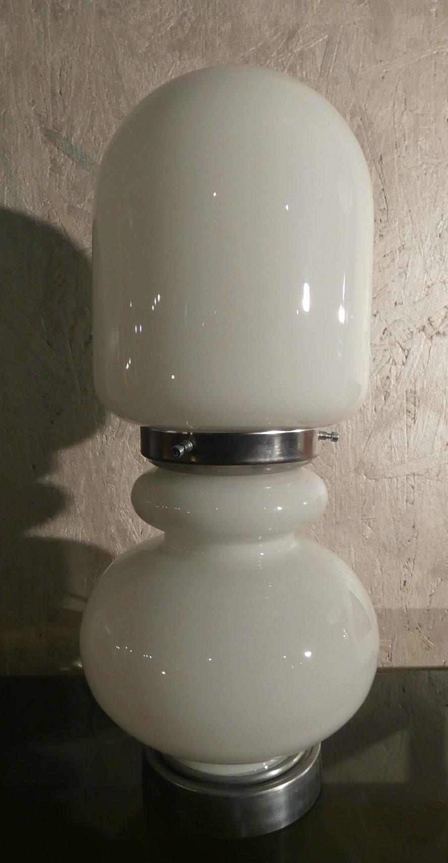 Table lamp produced in the 1970s by Mazzega glassworks. The pleasant round shapes and small size make it suitable for placement in any environment. Pleasing is the black rigadin pattern, contrasting with the milky white color of the lamp.

Le